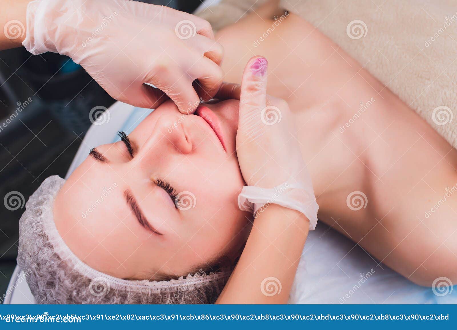 cosmetologist makes a buccal massage of the patient`s facial muscles.