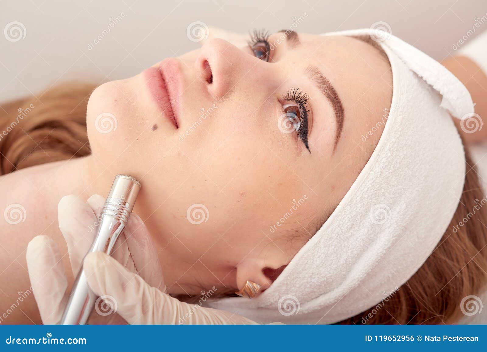 the cosmetologist makes the procedure microdermabrasion of the facial skin of a beautiful, young woman in a beauty salon