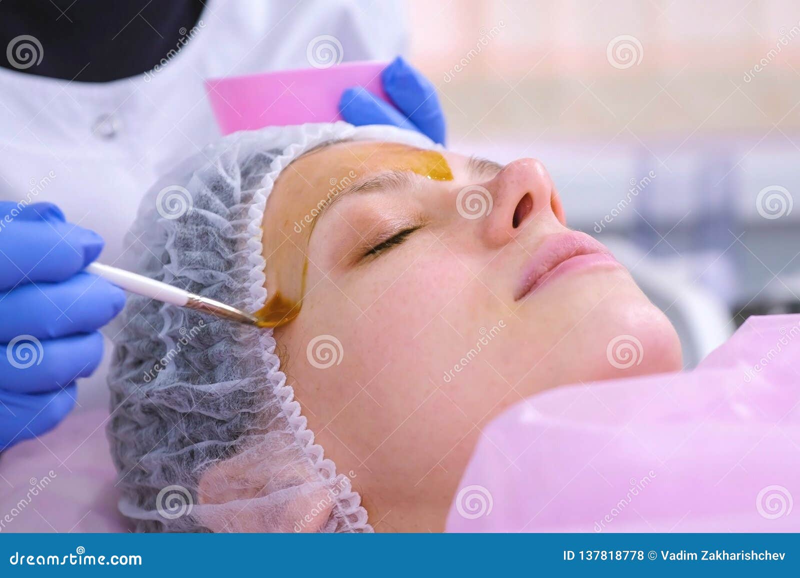 cosmetologist puts chemical peeling of the woman`s face with brush. cleaning the face skin and lightening freckles skin.