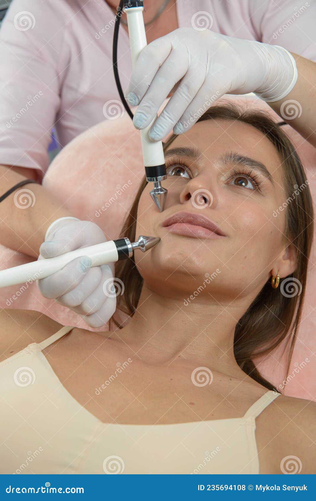 Beautiful Woman At Spa Clinic Receiving Stimulating Electric Facial Treatment From Therapist