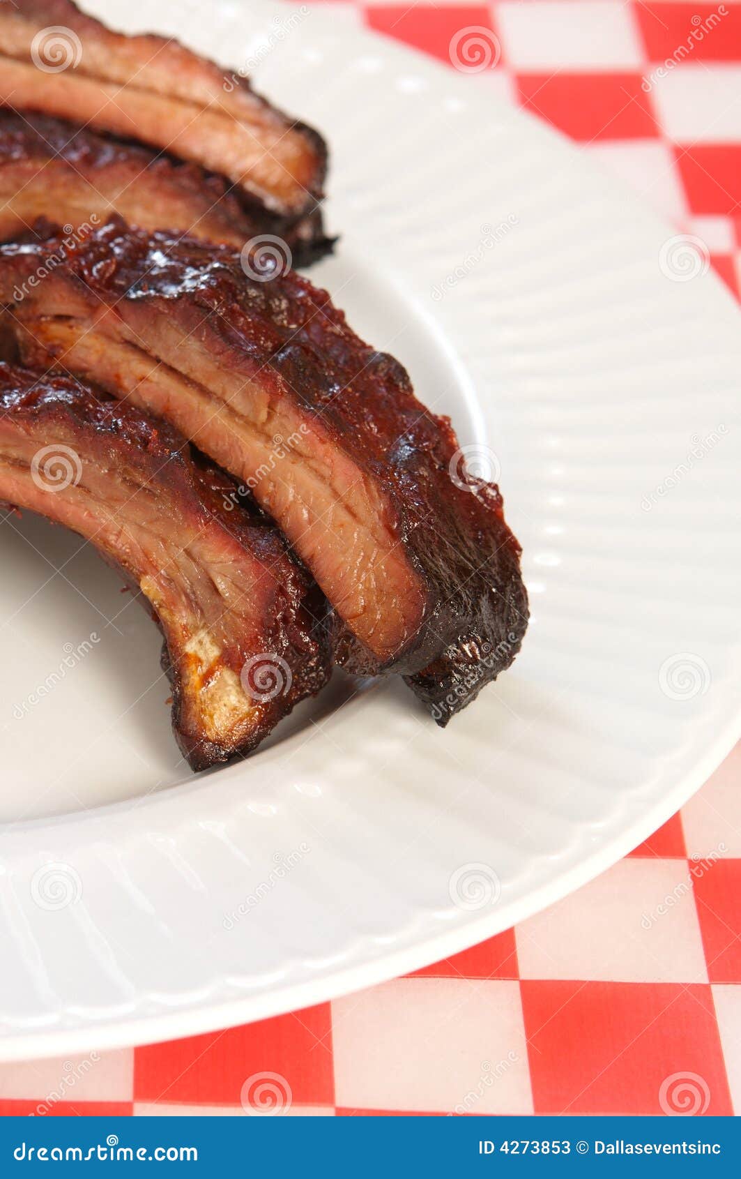 Costillas de la barbacoa en una placa blanca. Costillas de cerdo de repuesto de la barbacoa de Babyback en un tejido checkered del restaurante