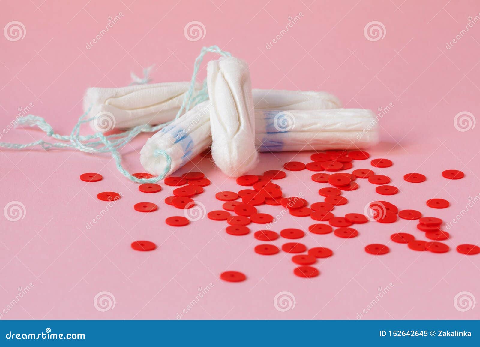 cotton tampons and red beads as blood drops   on pink background