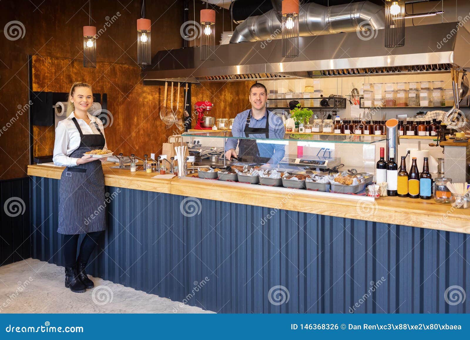 counter service at modern bistro with smiling waiters serving food Ã¢â¬â happy business owners in small restaurant with open kitchen