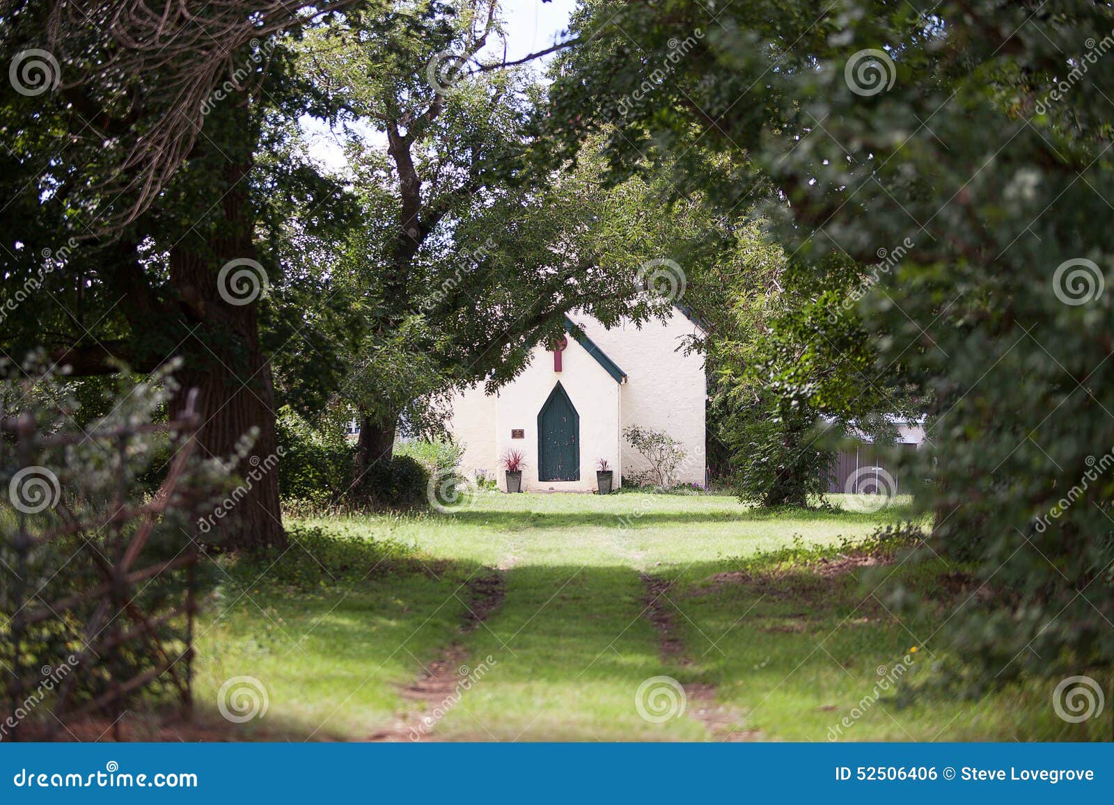 View of an old country Church through green trees and driveway