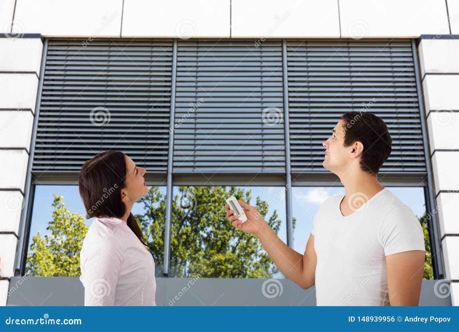 couple using remote to open window shutter