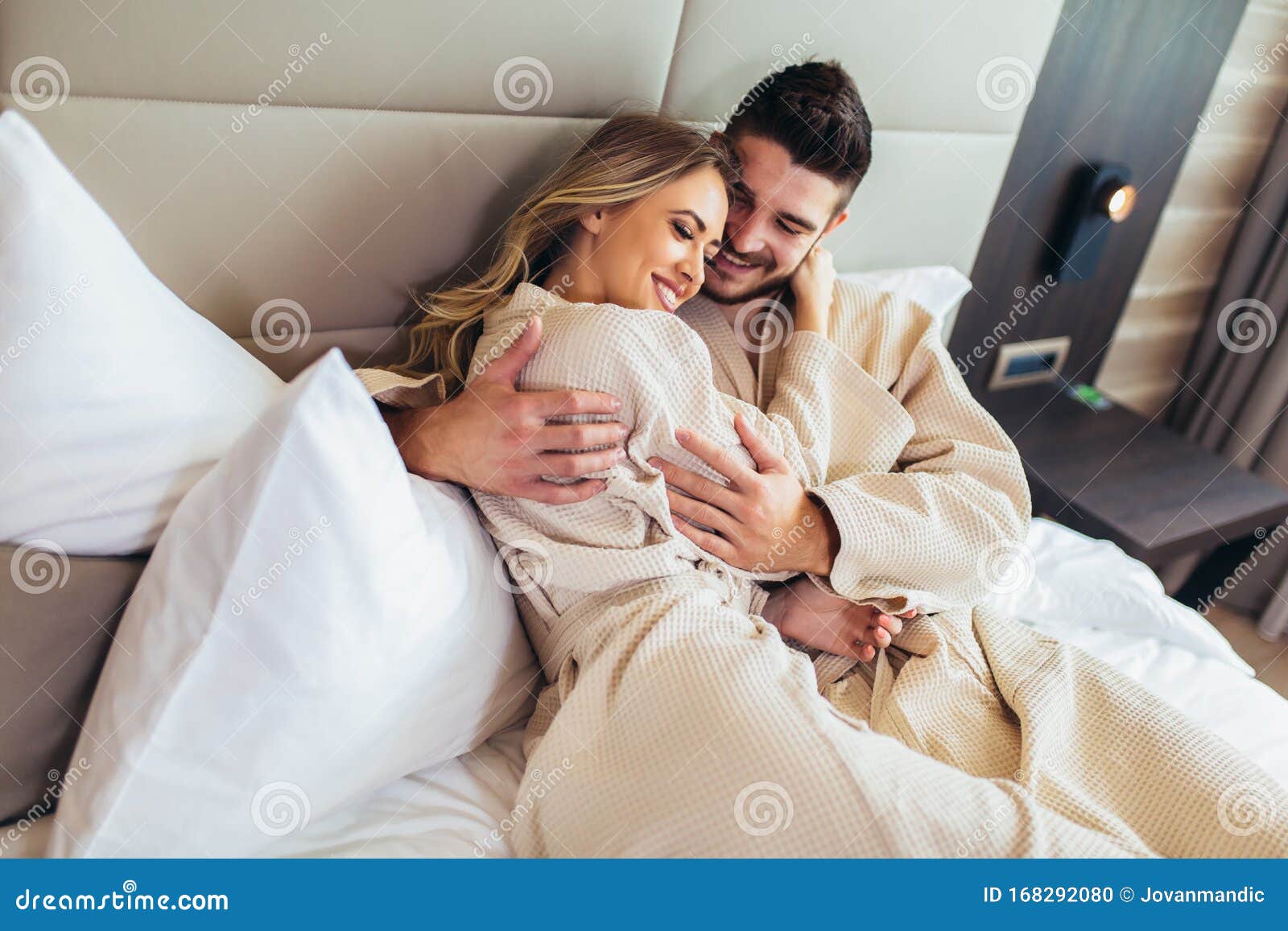 Couple In Bathrobes Lying On Bed In Hotel Room Stock Photo Image Of