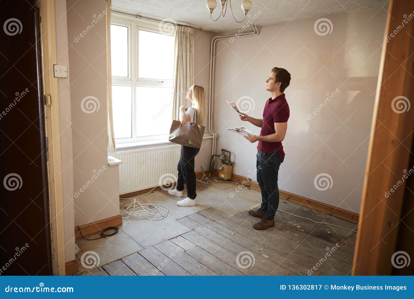 couple buying house for first time looking at house survey in room to be renovated