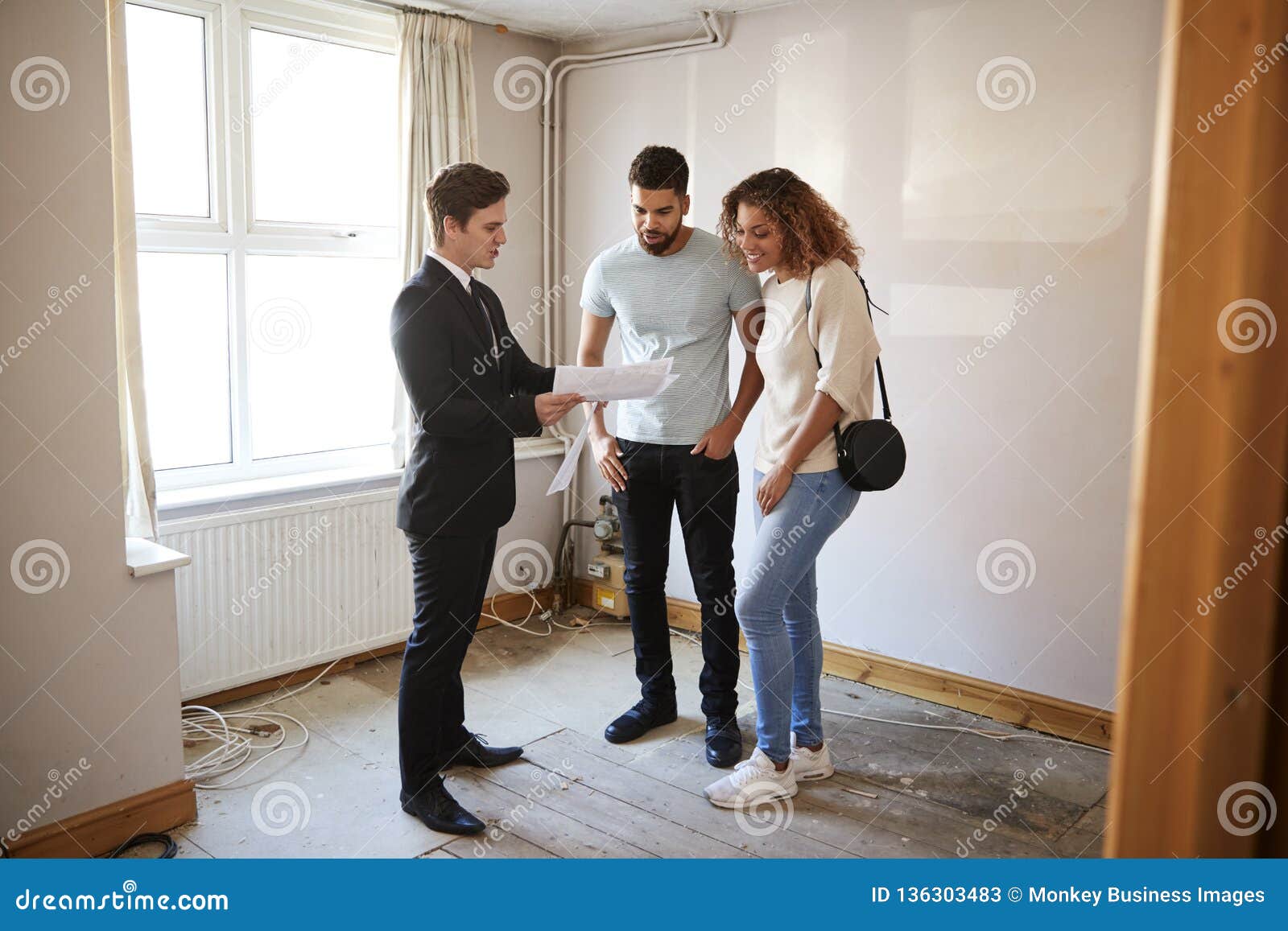 couple buying house for the first time looking at survey with realtor