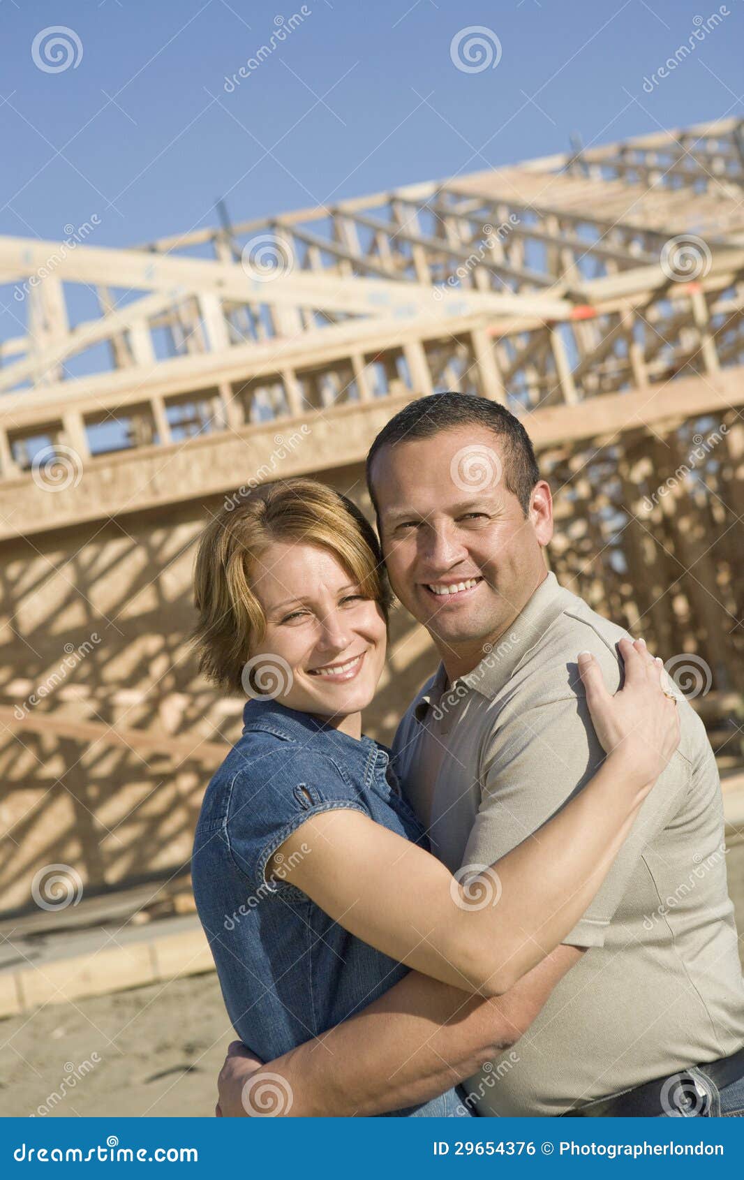 couple embracing in front of incomplete house