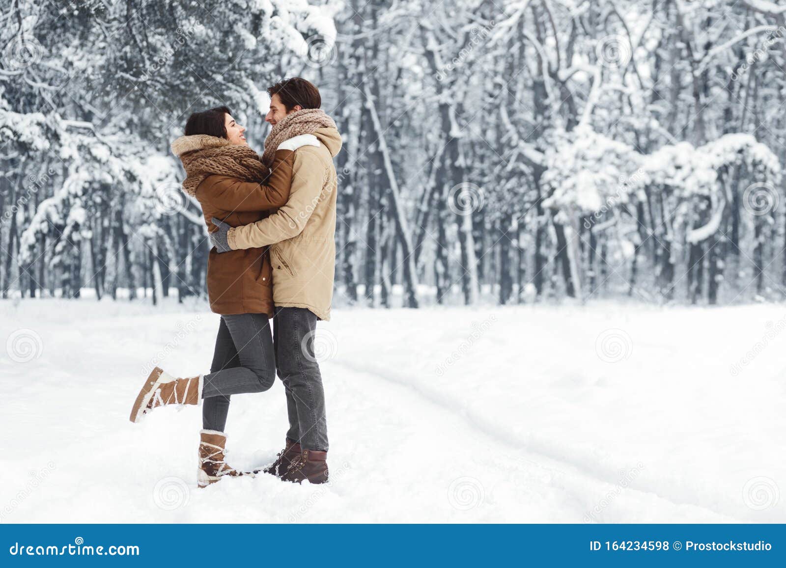 couple embracing standing in snowy winter forest in the morning