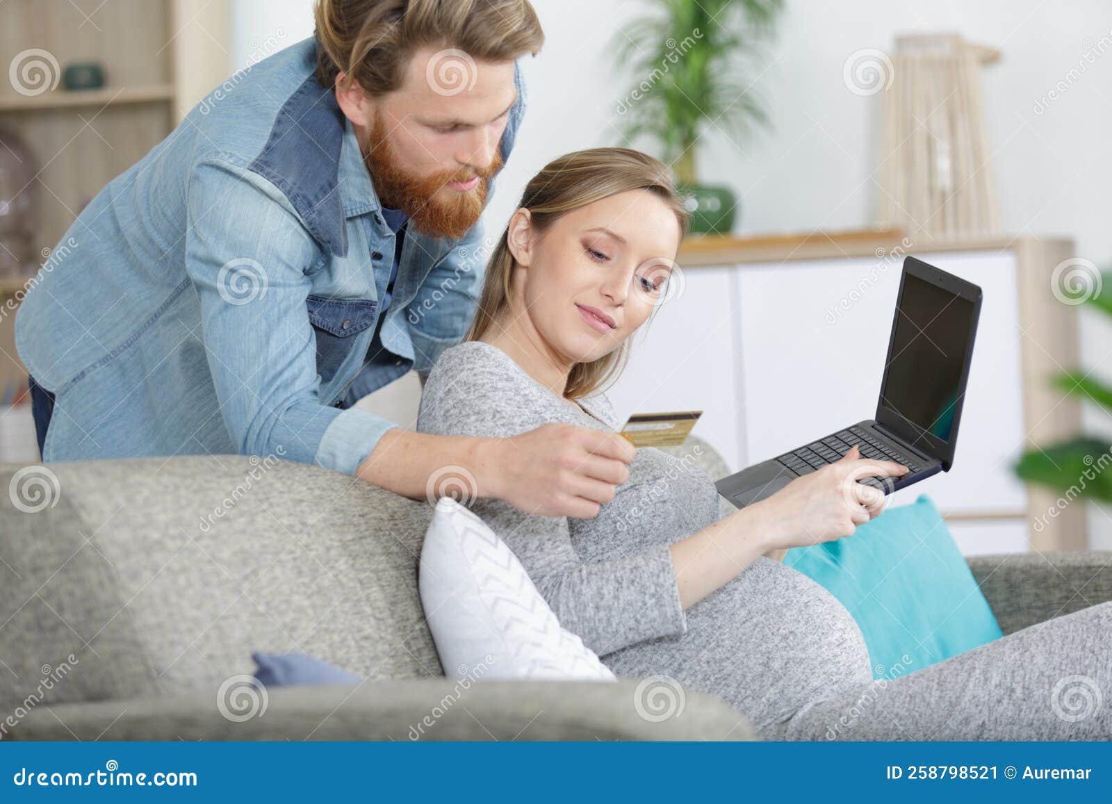 couple enjoying online shopping sitting on sofa at home