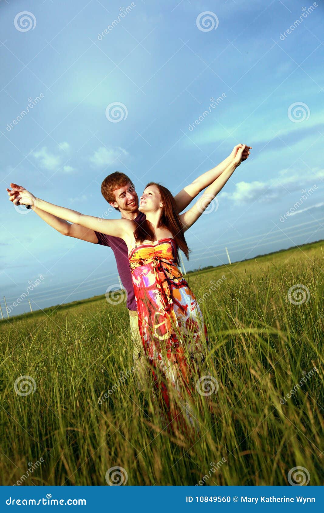 Couple in Field. A romantic young couple posing in a field with their hands stretched out.