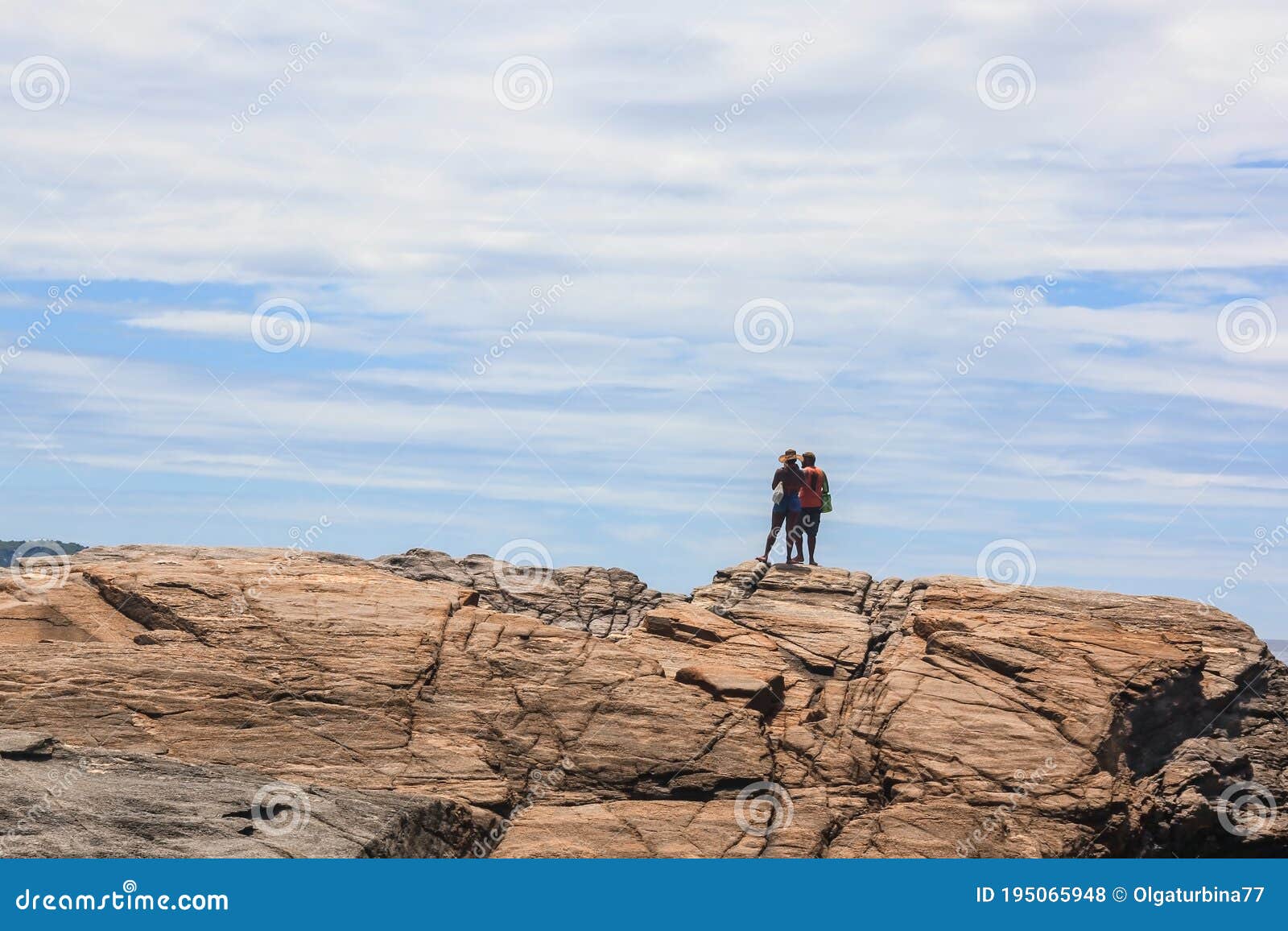 couple of happy hispanics people standing backs on top of cliff and overlooking stunning view to atlantic ocean