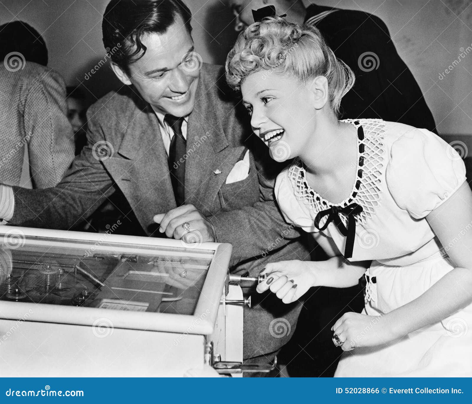 couple having fun and laughing next to a pinball machine