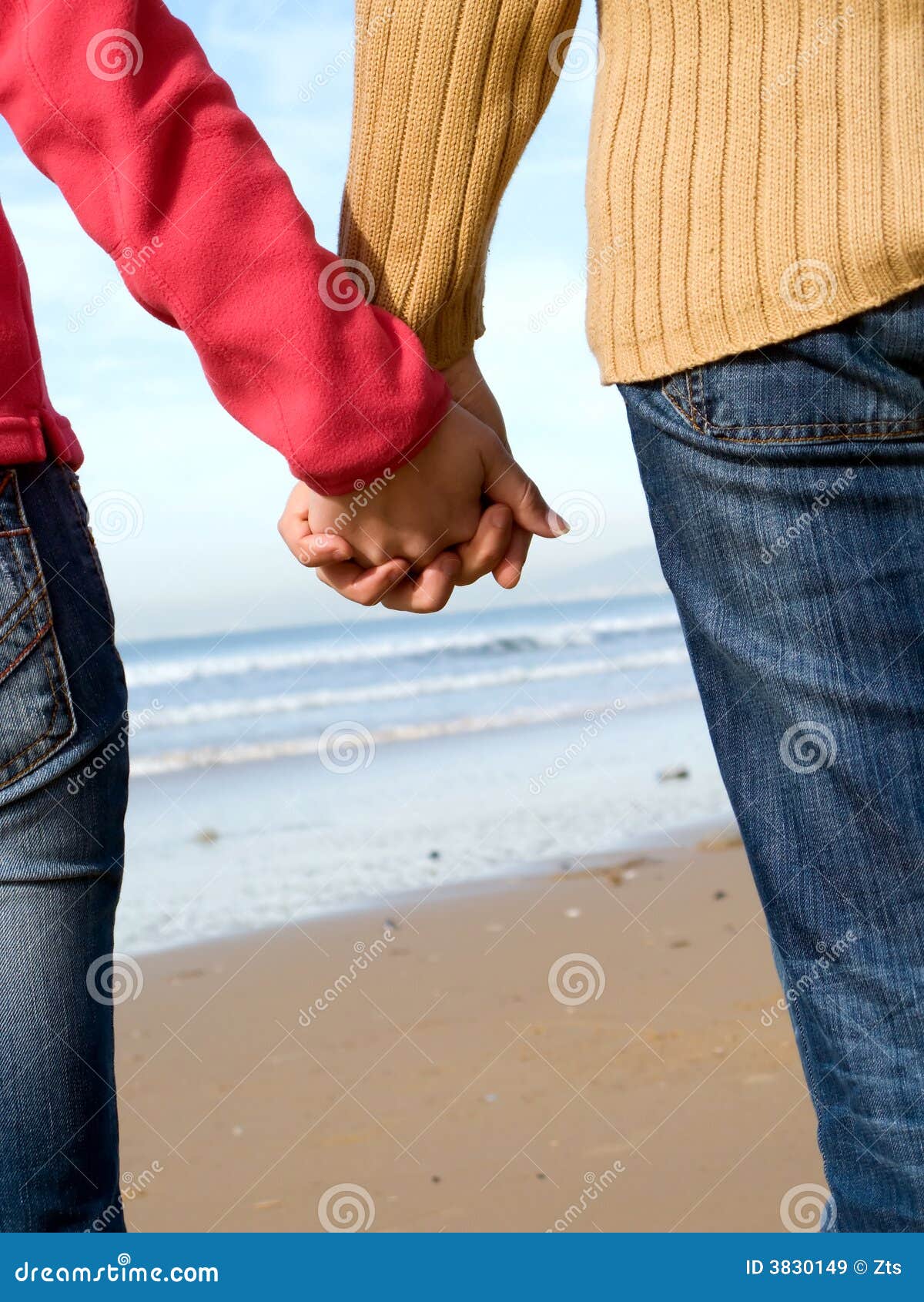 Lovers couple holding hands on beach at winter