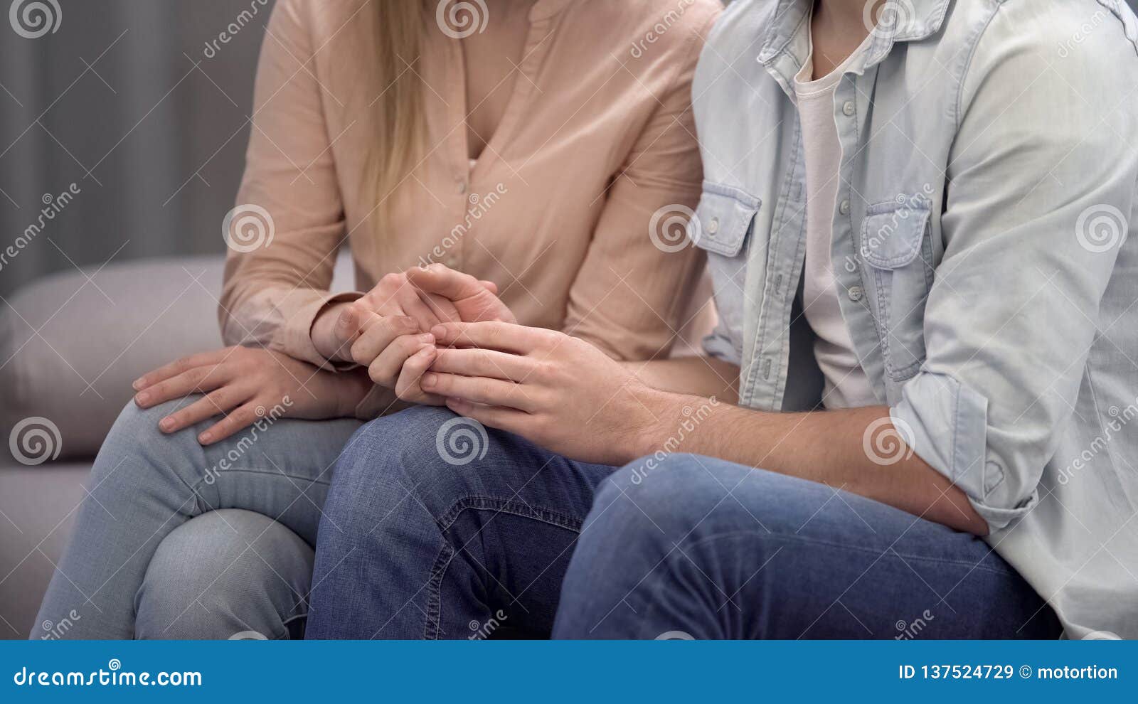 couple holding hands, sitting in waiting hall hospital, fertility consultation