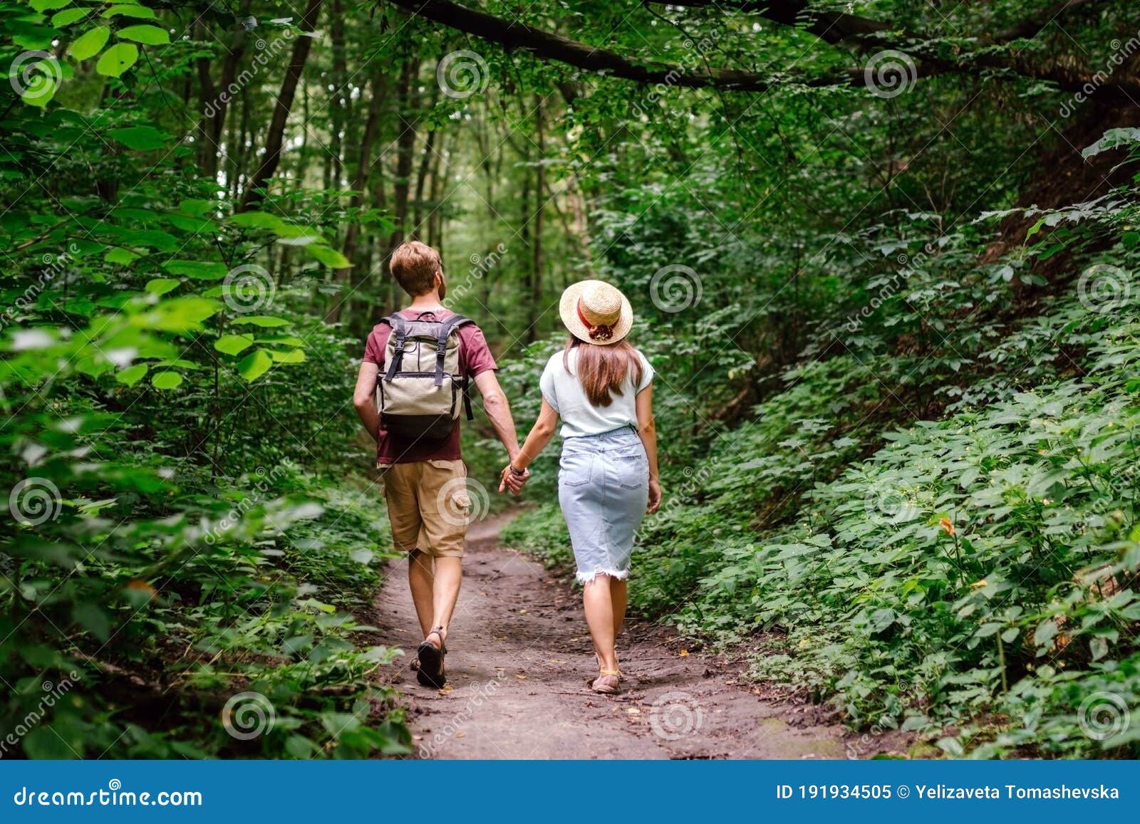 Couple Holding Hands Walking In Forest Back View