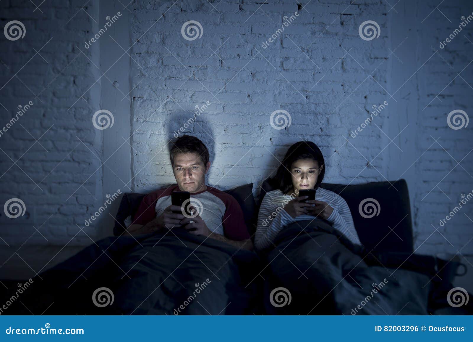 Couple At Home In Bed Late At Night Using Mobile Phone In Relationship Communication Problem