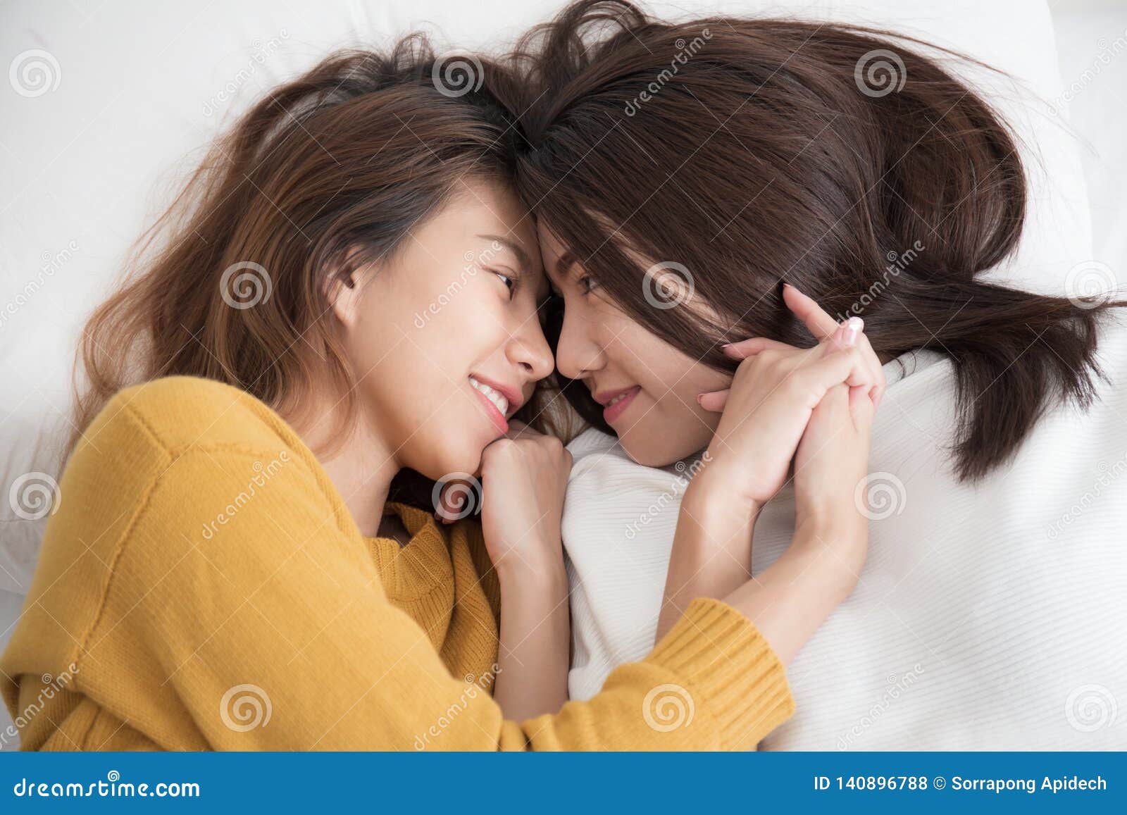 Couple of Homosexual Women on White Bed,Lesbians Asian Women are Smiling and Catching on White Bed Stock Photo pic photo photo