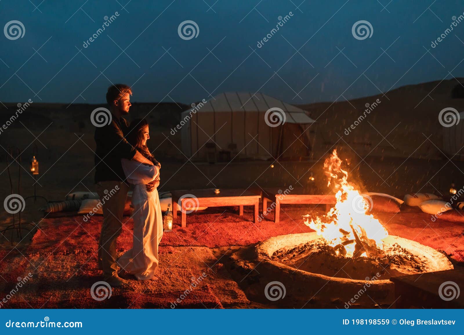 couple hug in love near big campfire. romantic night in glamping desert camp