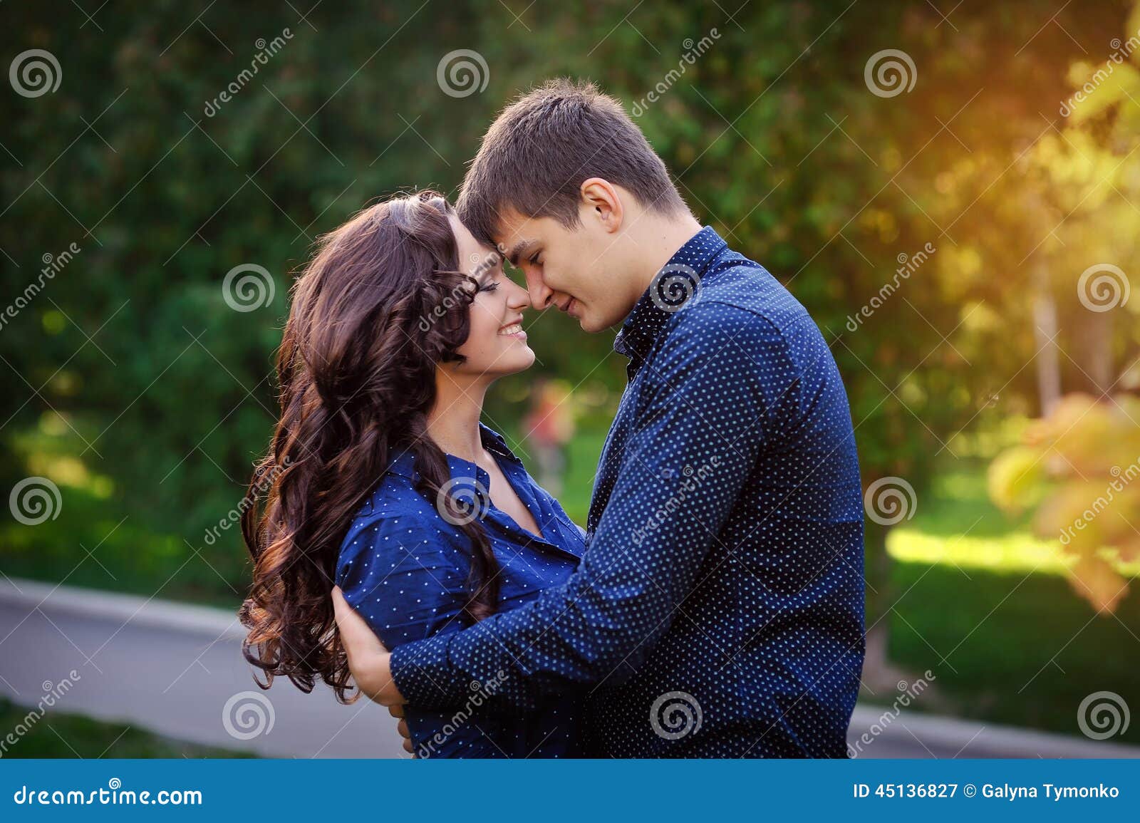 Couple hugging in a park seated in a bench