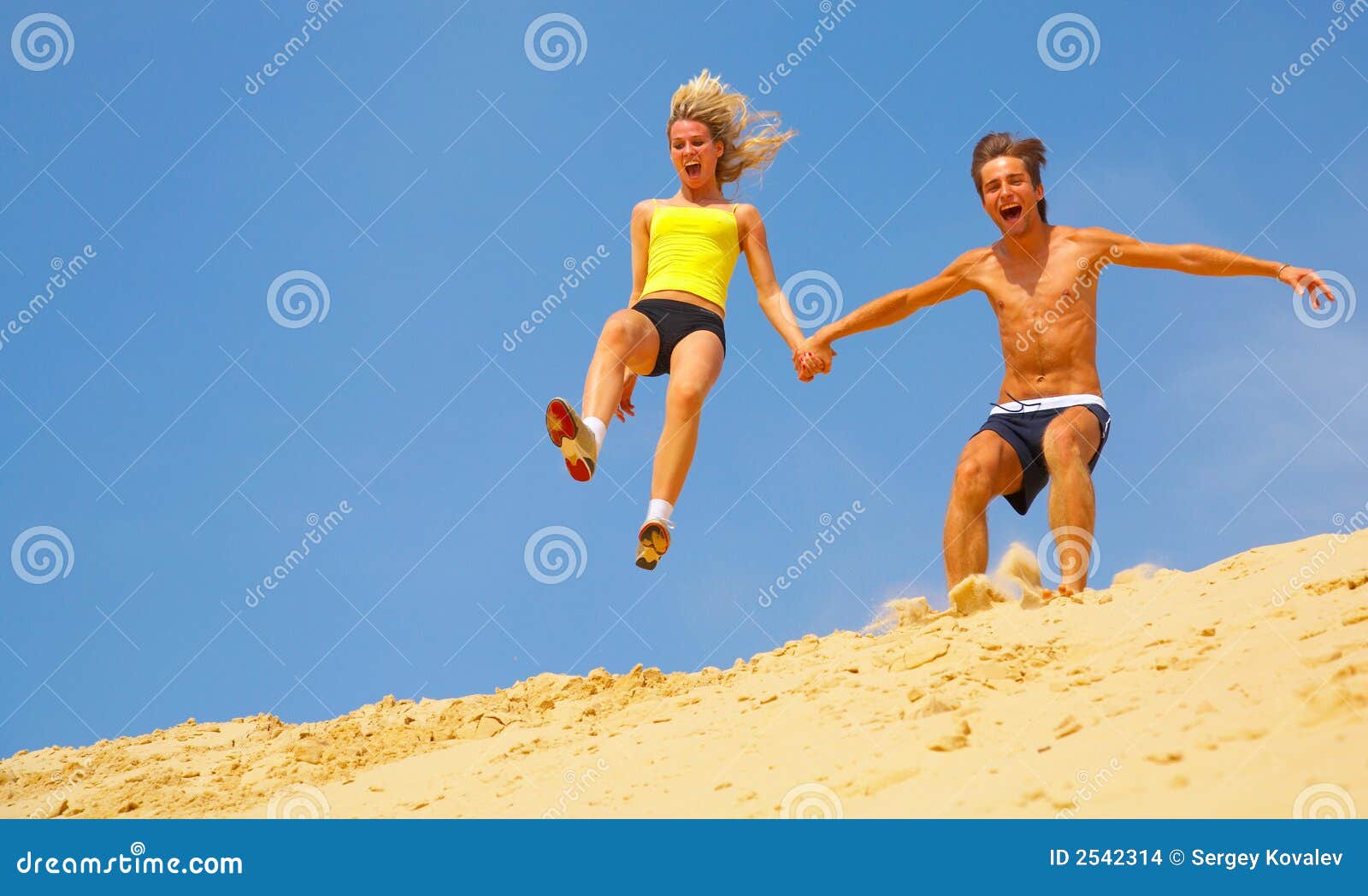 Couple Jumping Off Sand Dune Stock Photo Image of smiling, blue 2542314