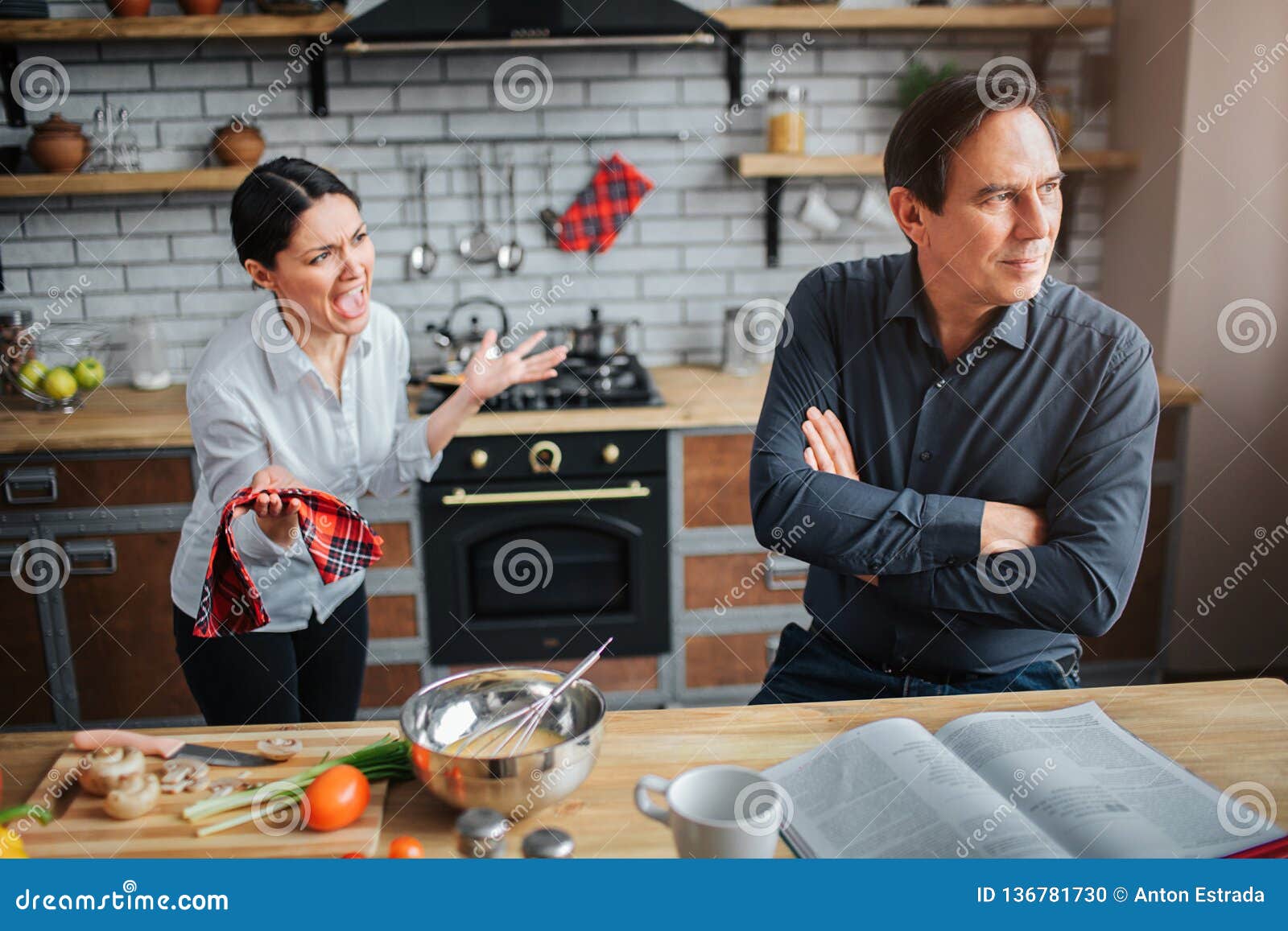 couple in kitchen. theey have argue. guy doesn`t listen to woman. she try to talk to him. they are upset and unhappy.