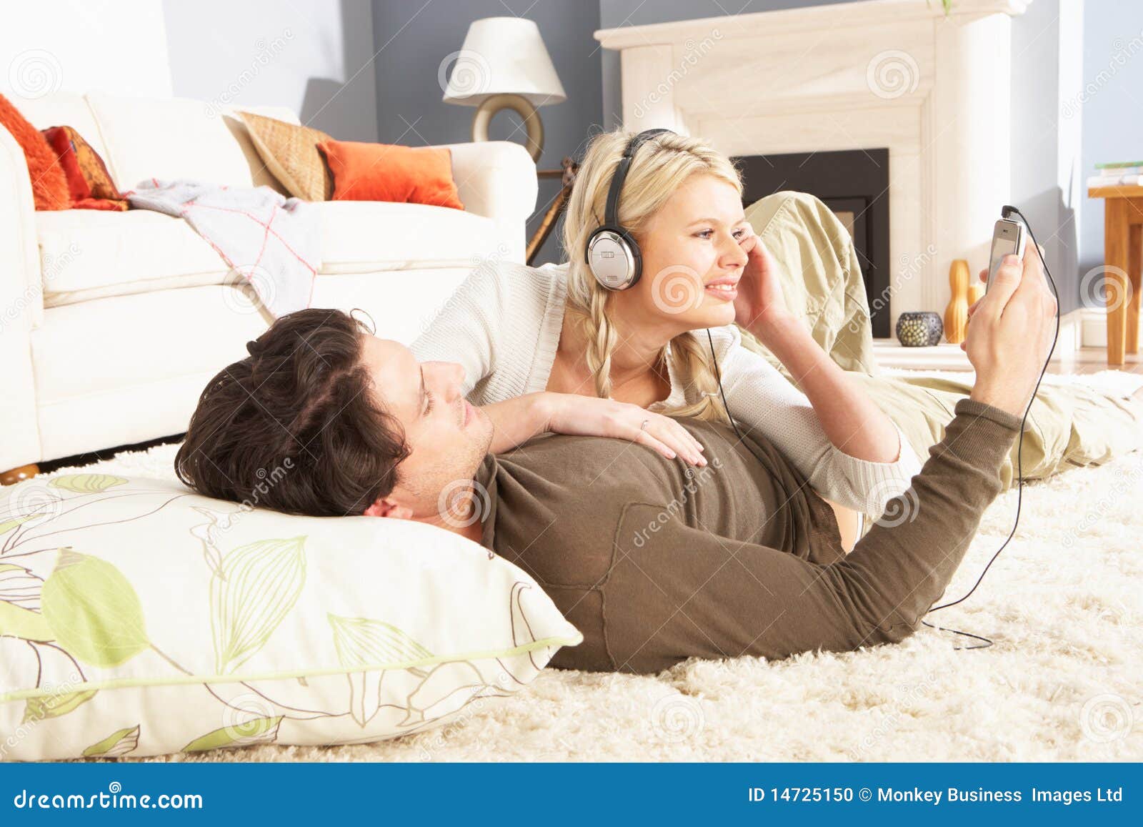 couple listening to mp3 player laying on rug