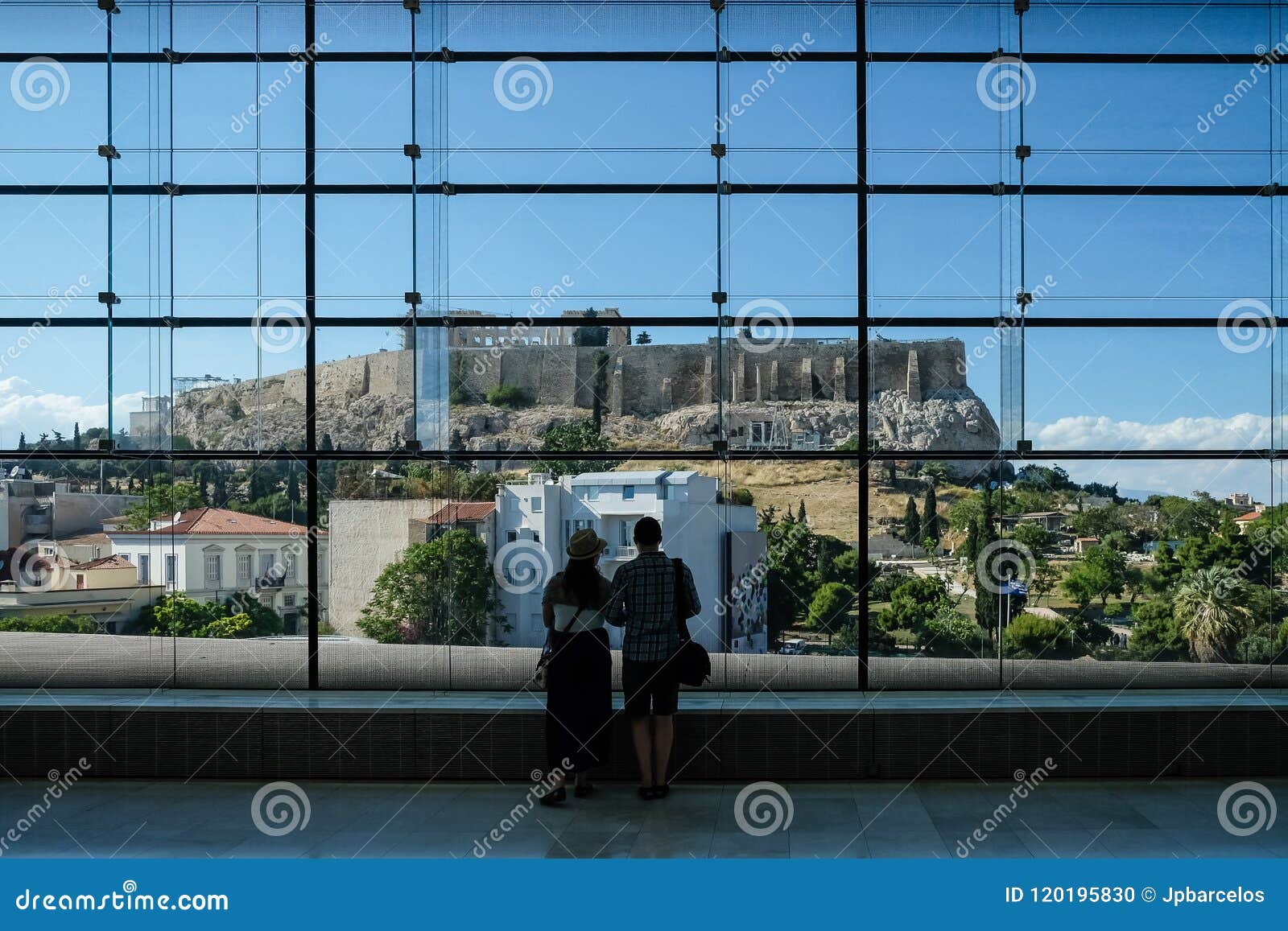 couple looking out at the acropolis throught huge glass window in the acropolis museum. athens, greece.
