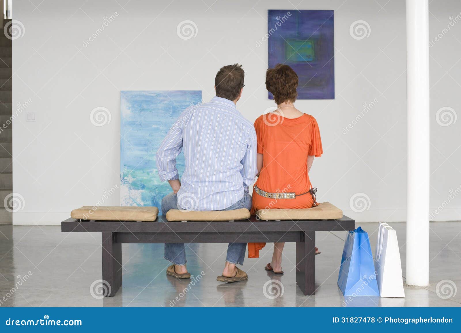 couple looking at paintings in art gallery