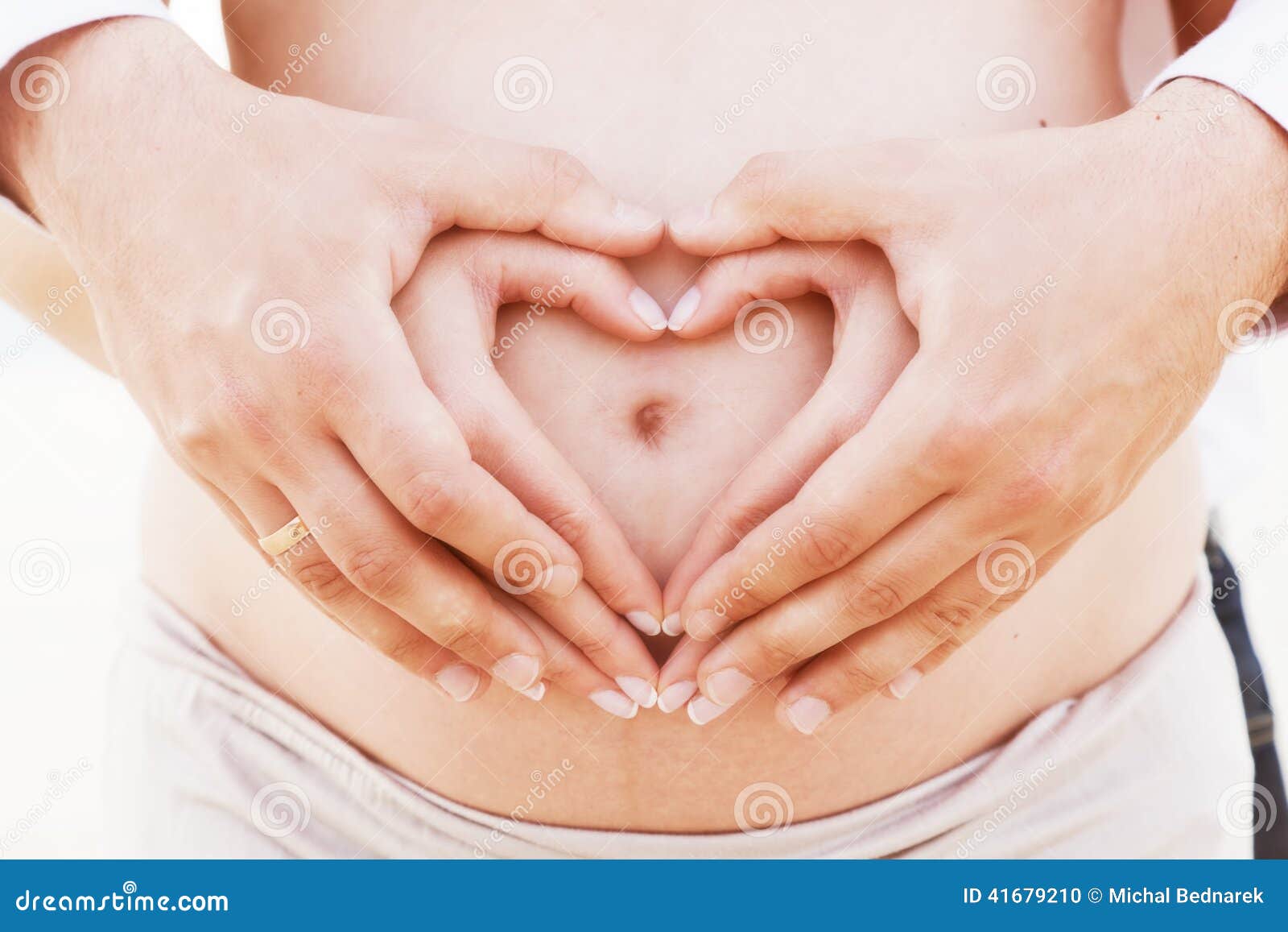 a couple making a heart  on the pregnant belly