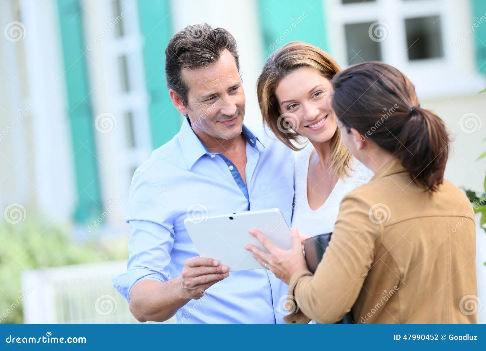 couple meeting real-estate agent in front of their new home