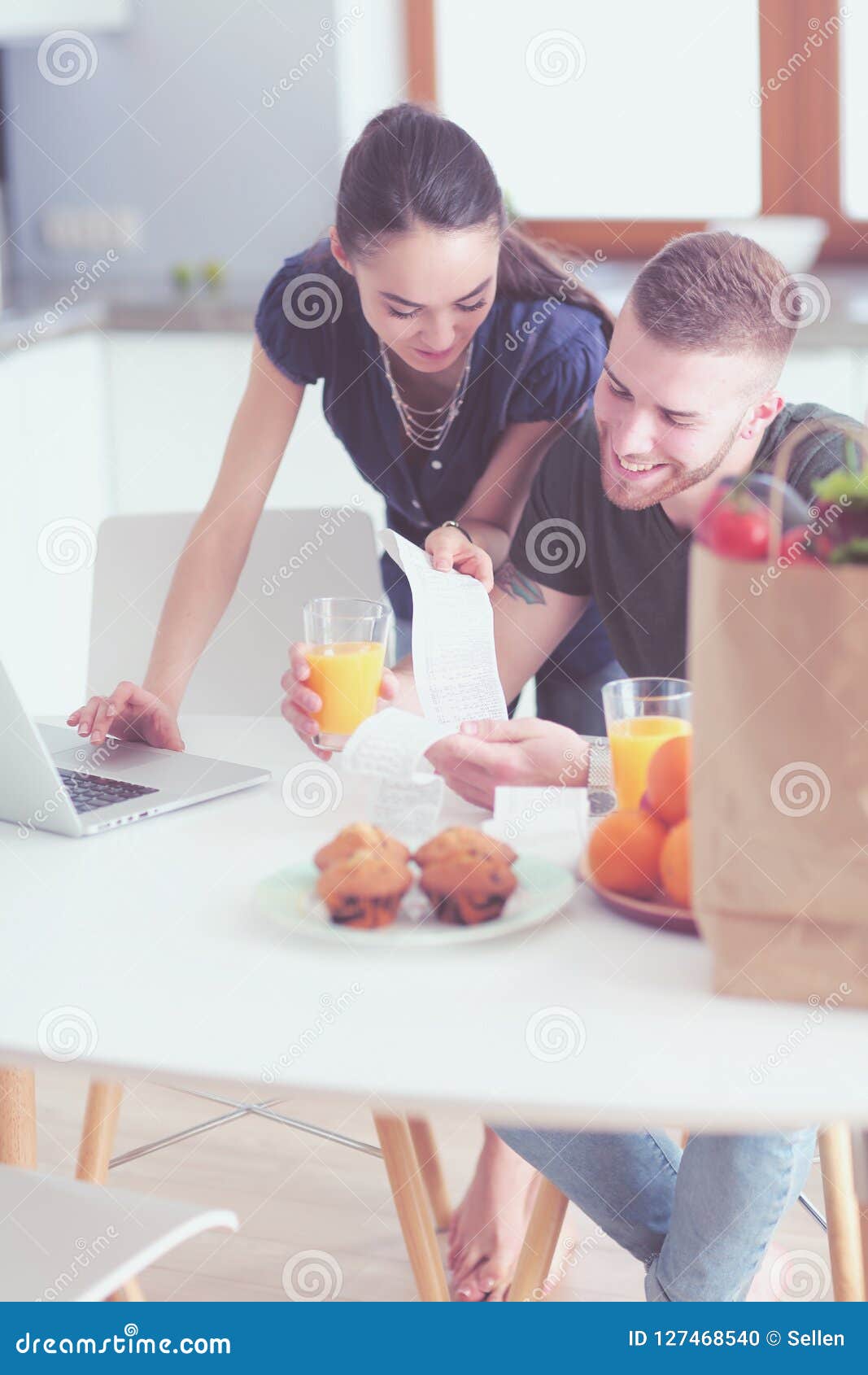 Couple Paying Their Bills with Laptop in Kitchen at Home Stock Photo