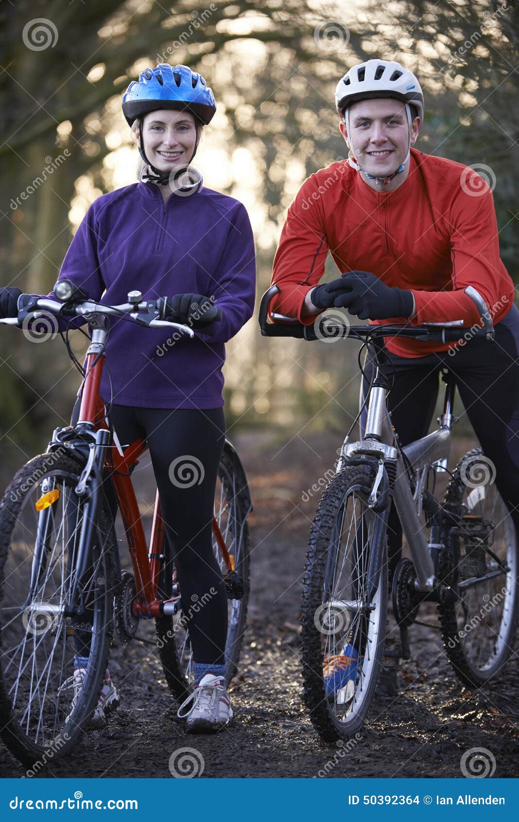 couple riding mountain bikes through woodlands