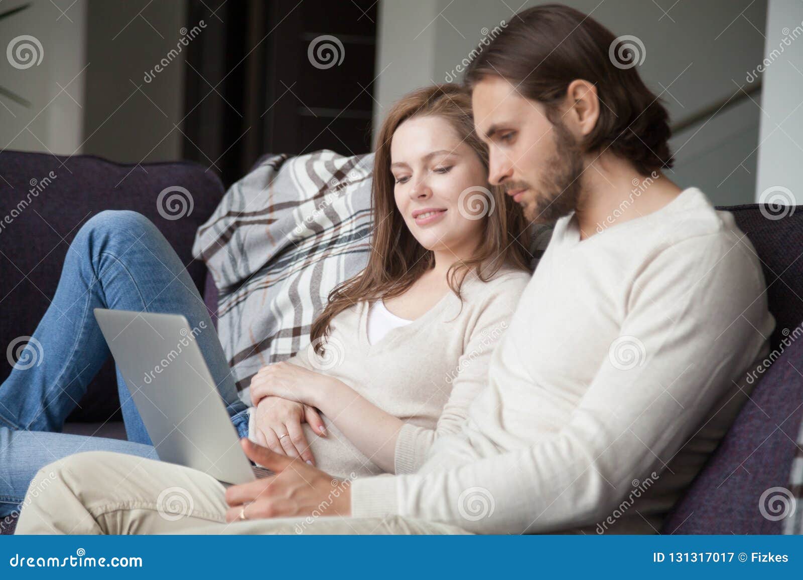 Couple Sitting Together On Couch Using Laptop Stock Image