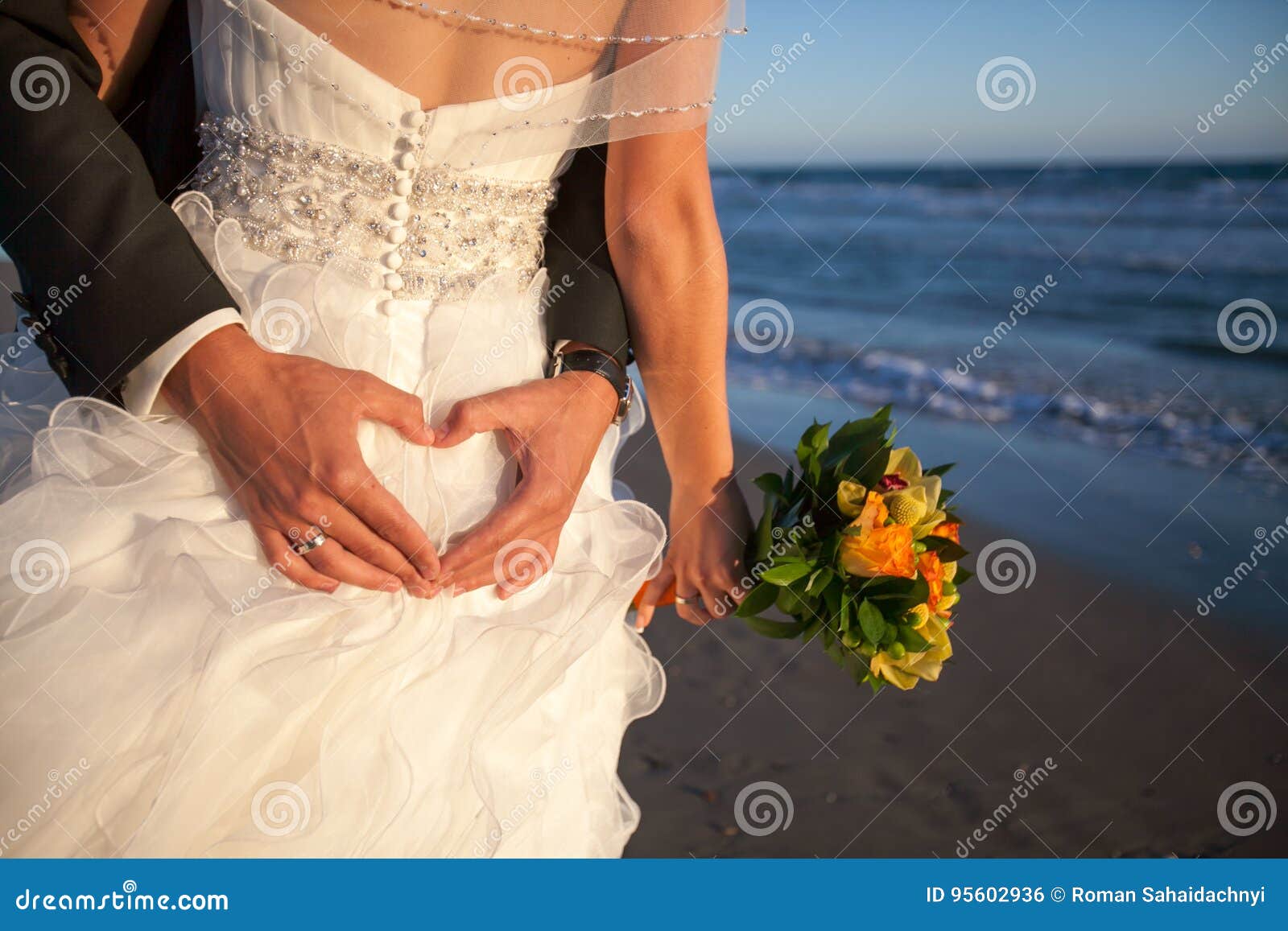 couple smiling and embracing near wedding arch on beach. honeymoon on sea or ocean