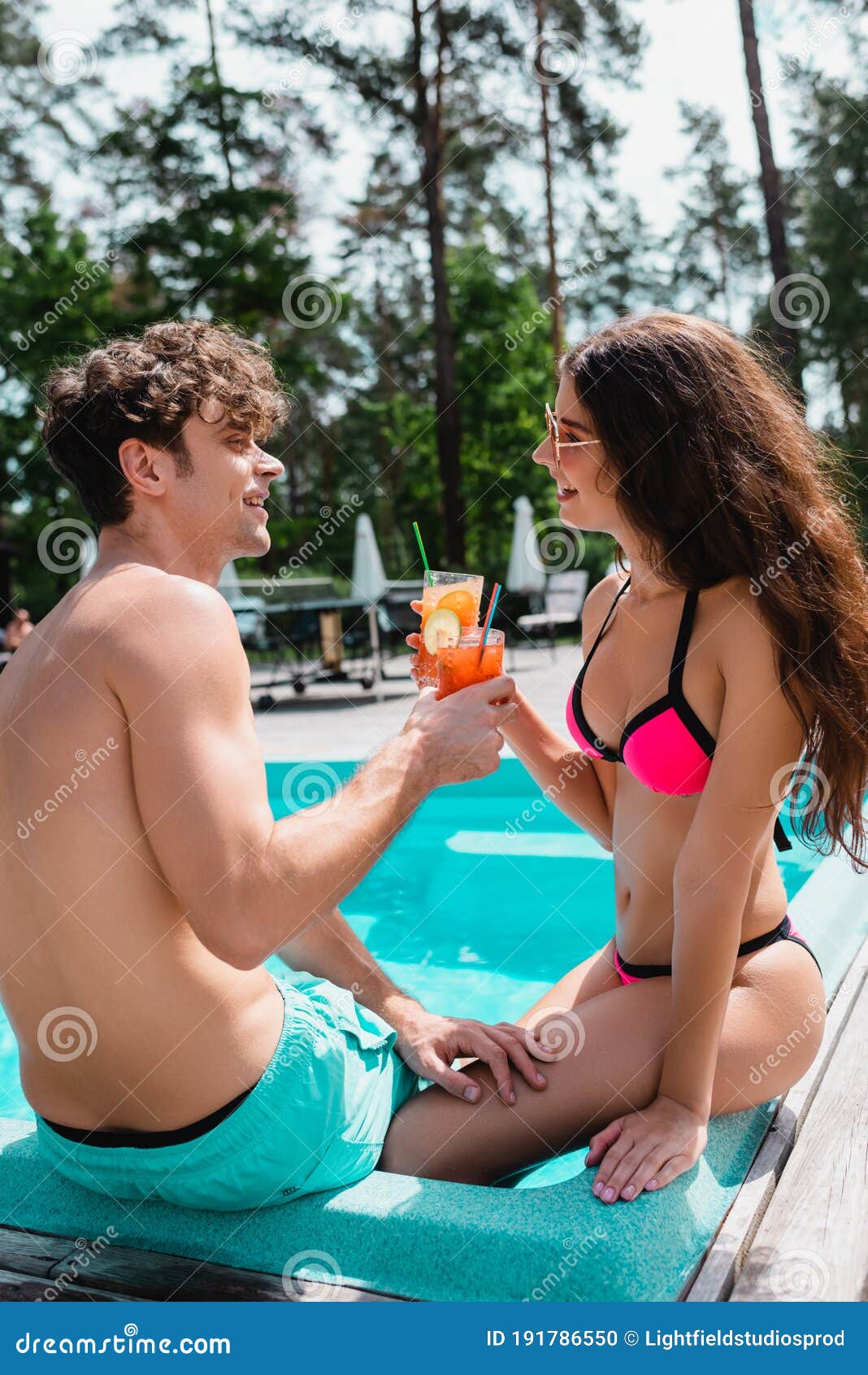 Couple in Swimwear Holding Alcohol Cocktails Near Swimming Pool