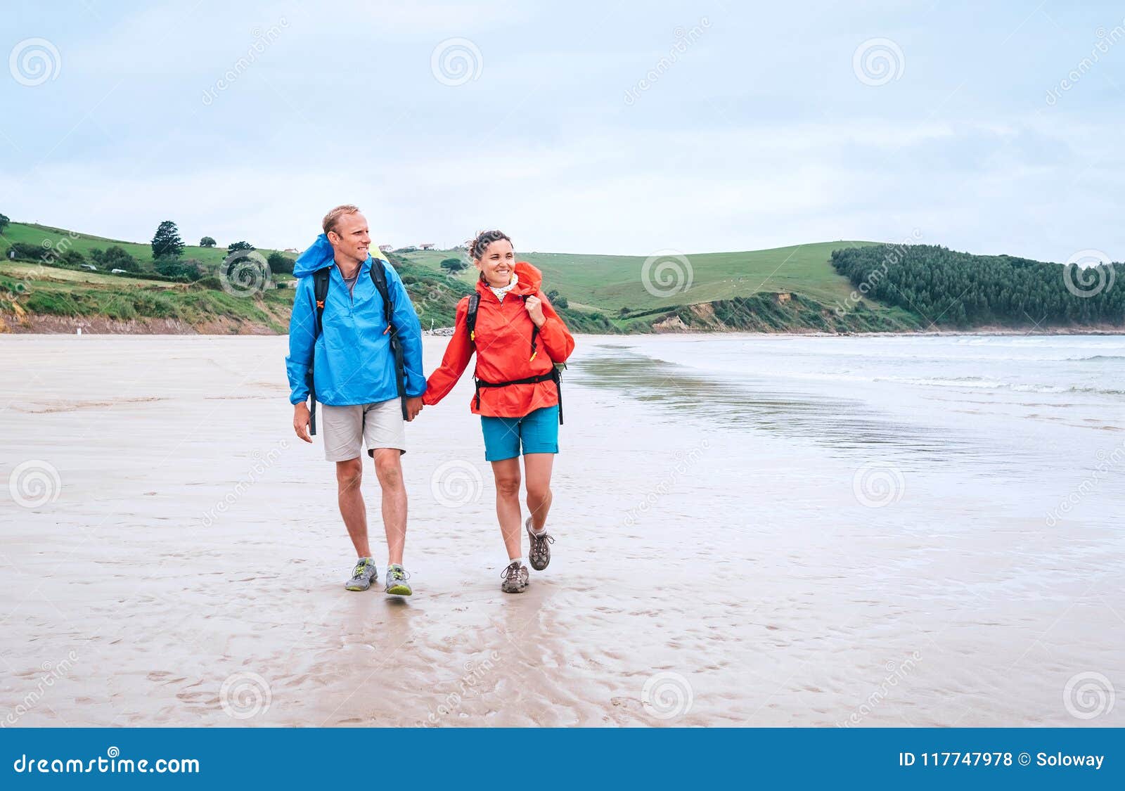 couple travelers walk on the coast of biskay bay in north spain, part of camino del norte famous piligrims route
