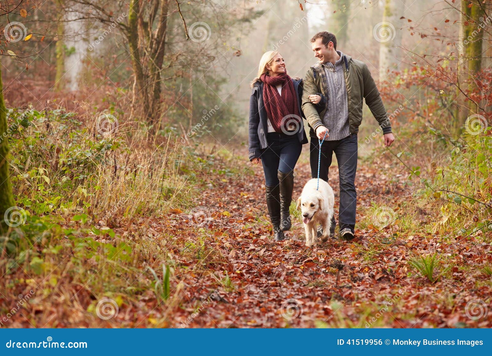 couple walking dog through winter woodland