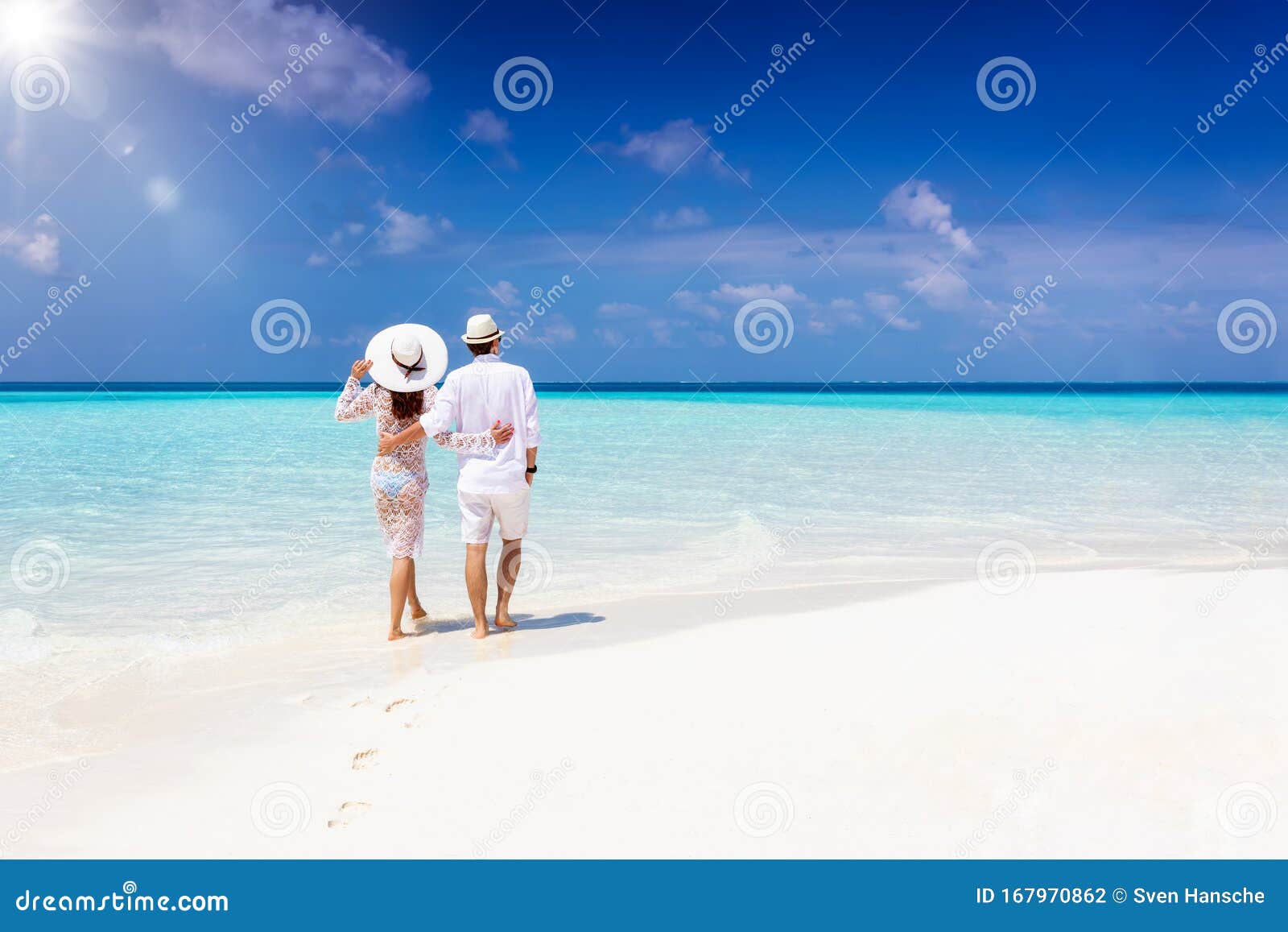 couple walks hugging down a tropical beach during their vacation