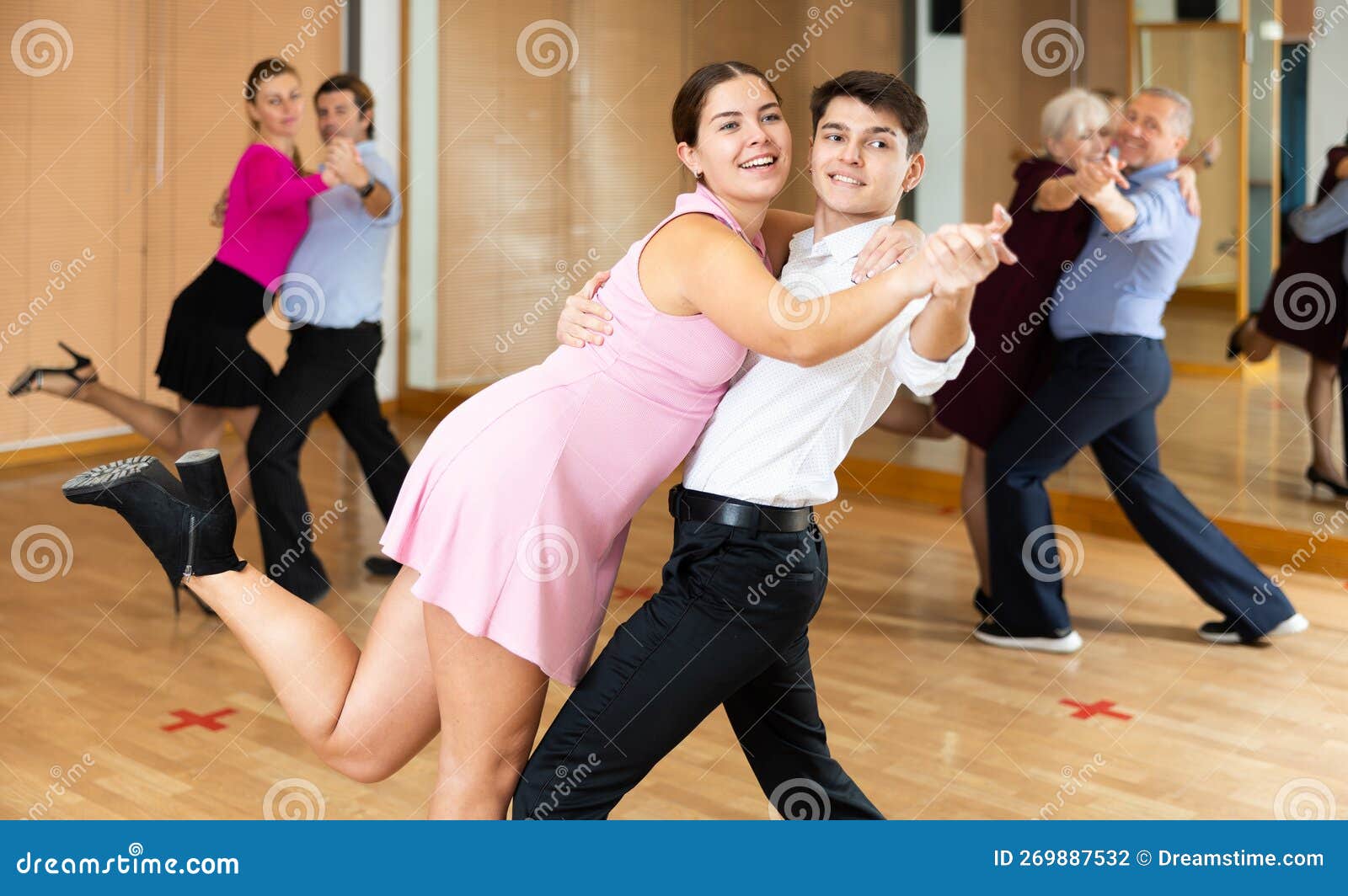 Cheerful Young Guy And Girl Practicing Ballroom Dances In Ballroom 