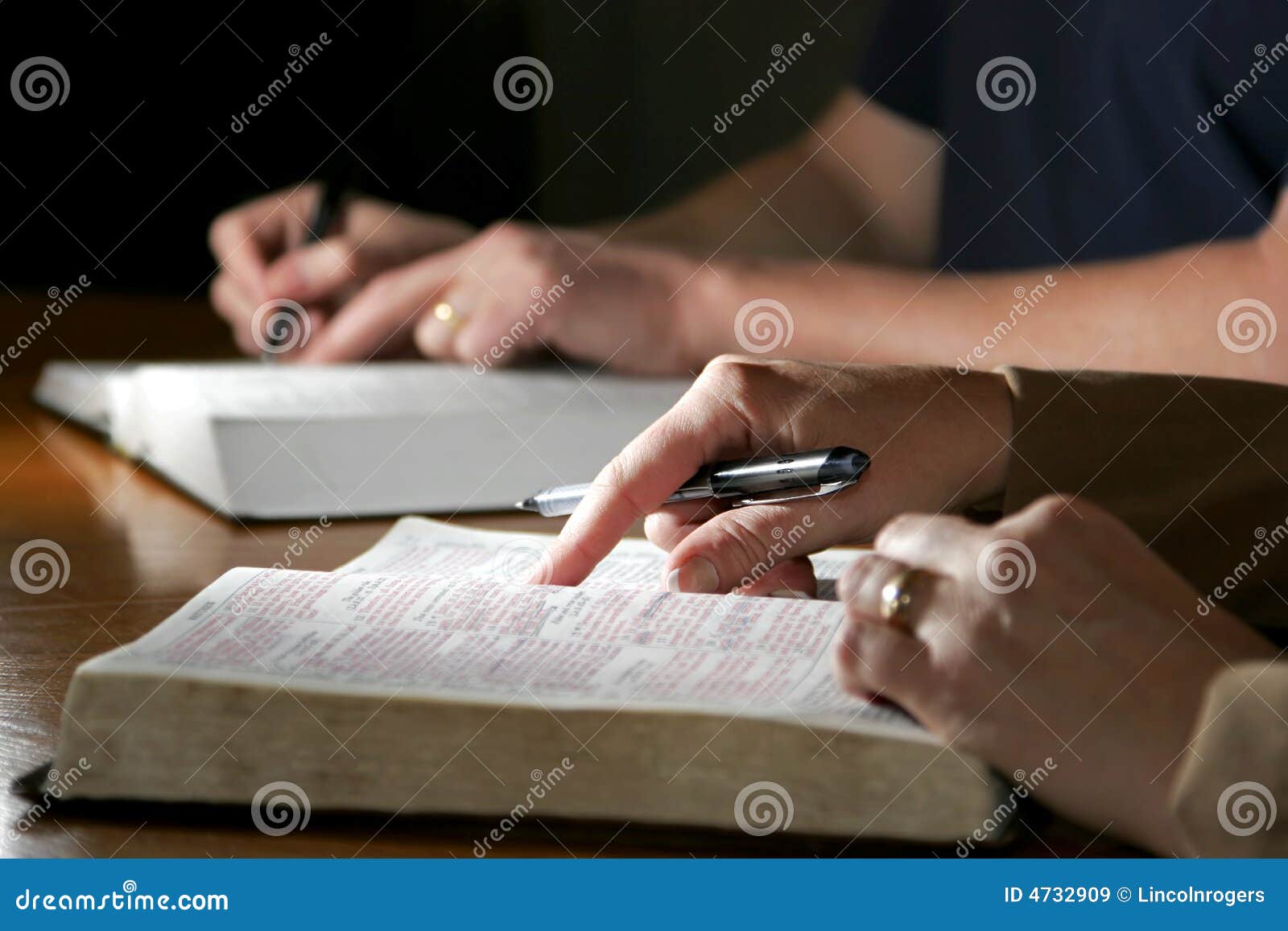 Couples d'étude de bible. Un homme et une femme étudient le togther de bible sainte (image chrétienne, point peu profond d'orientation sur la main de pointage de la femme de plan).