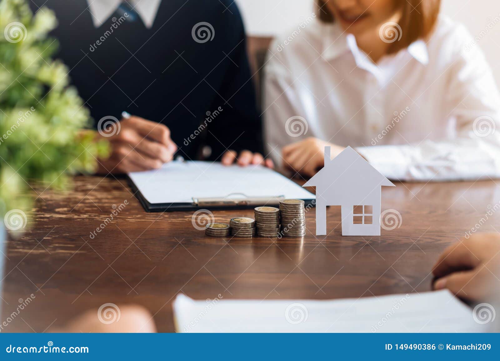 couples signed a contract to buy a house from the broker. coin to stack money and model houses placed on the table.
