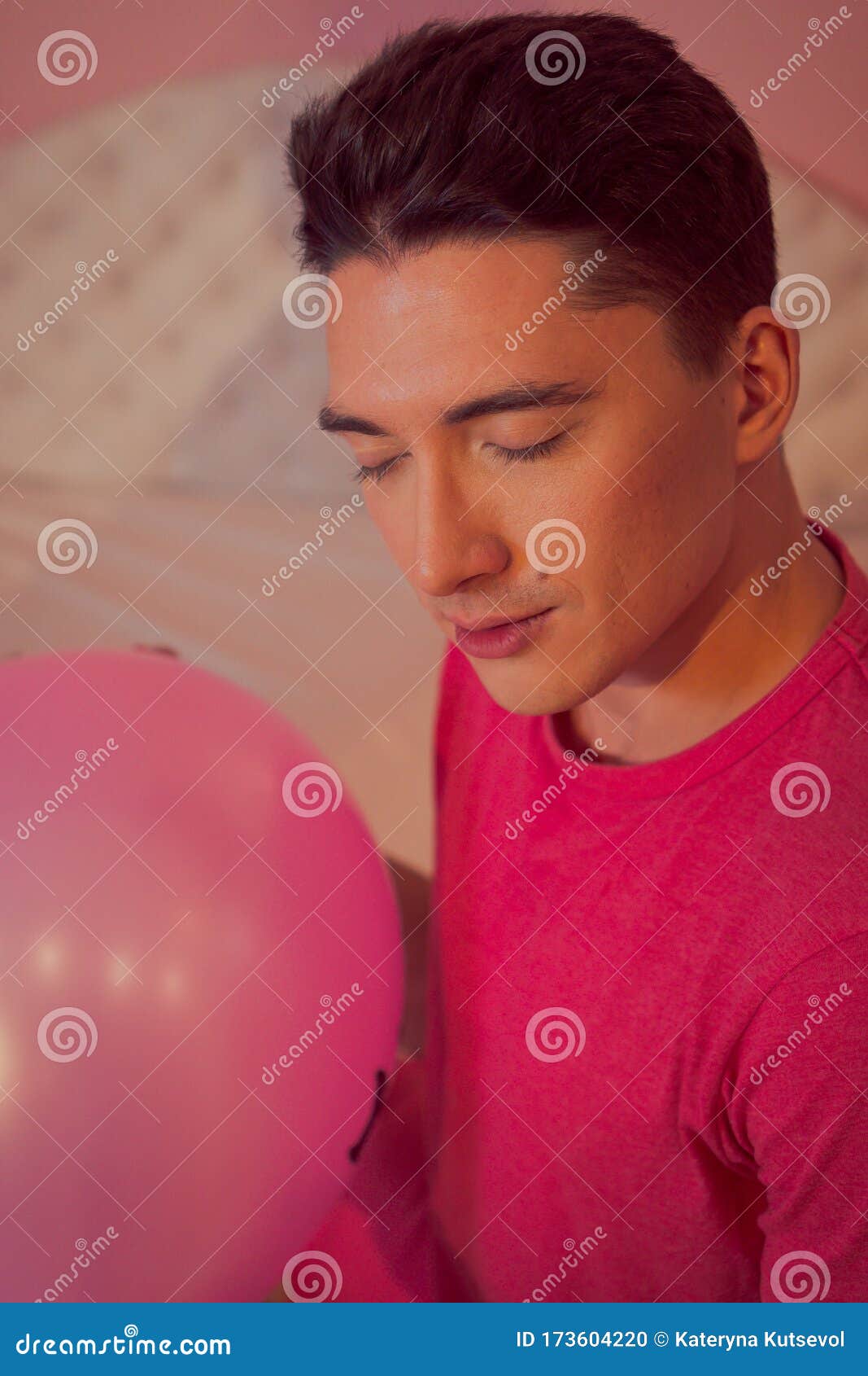 Courageous man holds a ball and closes his eyes. Young man thought and closed his eyes. Holds an inflatable purple large ball