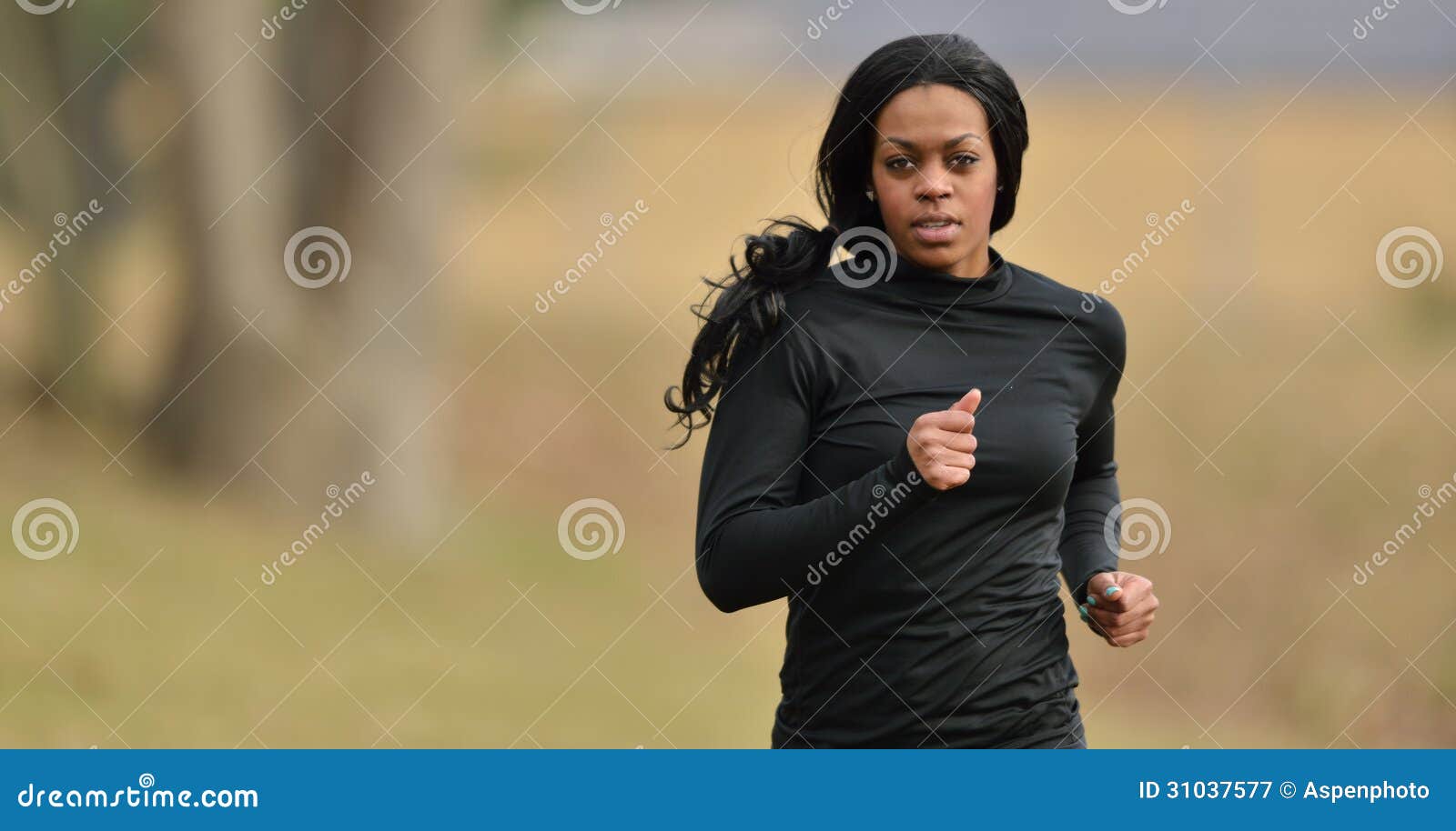 Coureur attrayant de taqueur de femme d'Afro-américain. Jeune femme attirante d'Afro-américain dans la vitesse noire de forme physique pulsant en parc - temps froid