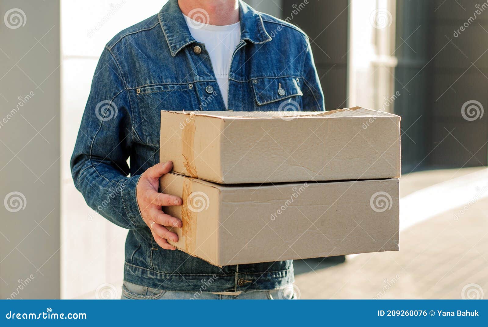 courier in a face mask with a box in his hands. portrait from the waist up. delivery man concept.. outdoor