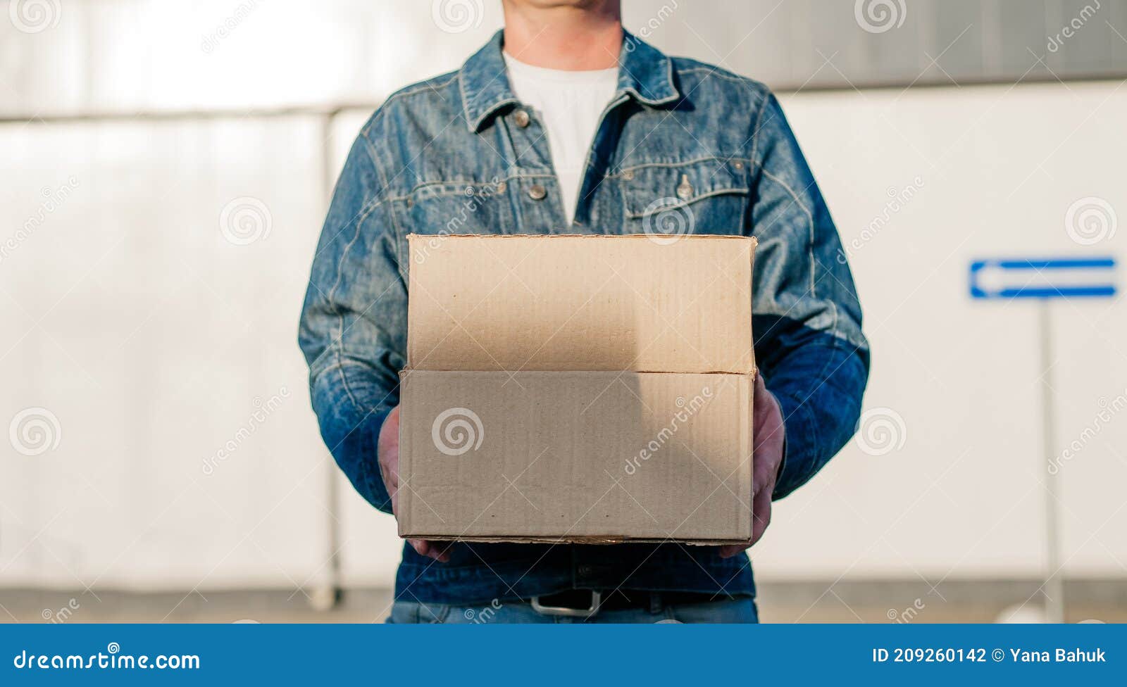 courier in a face mask with a box in his hands. portrait from the waist up. delivery man concept.. outdoor