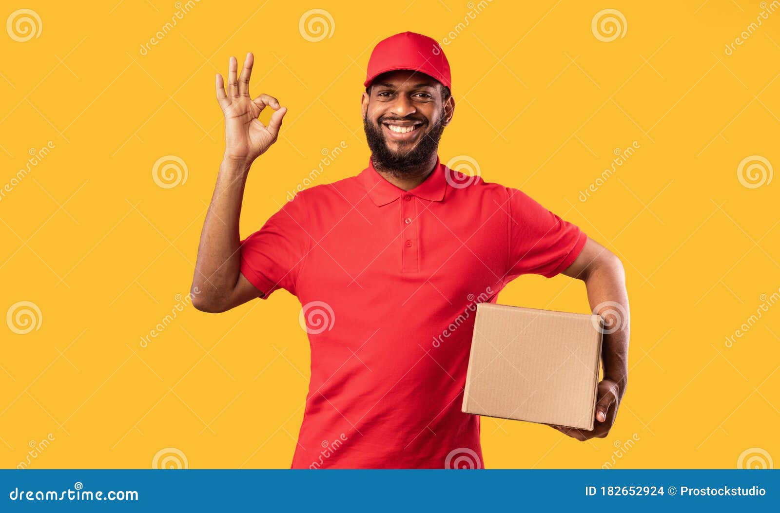 courier guy holding cardboard box gesturing okay on yellow background
