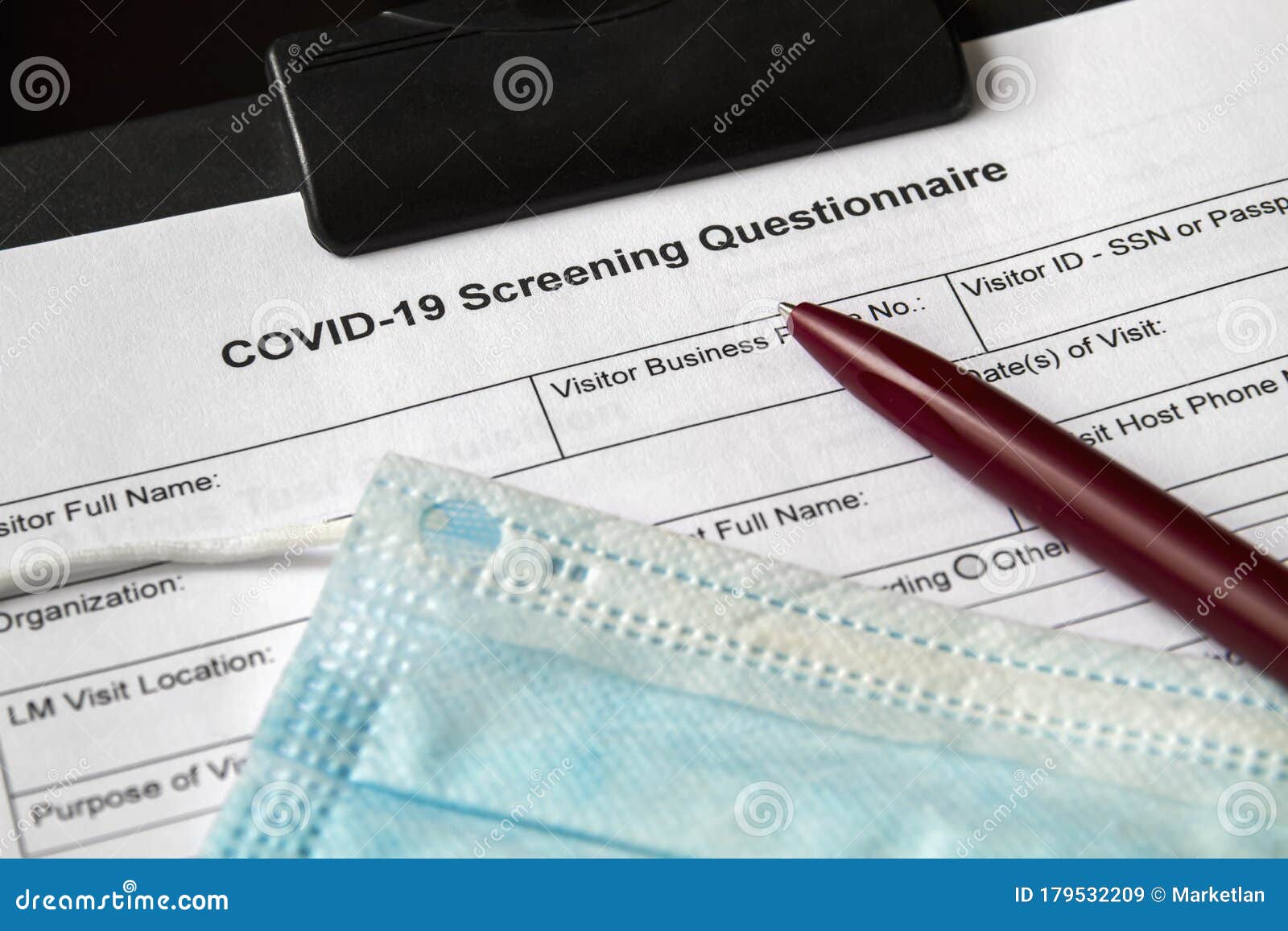 covid-19 screening questionnaire form with medical mask and a pen on it. healthcare and medical concept. closeup