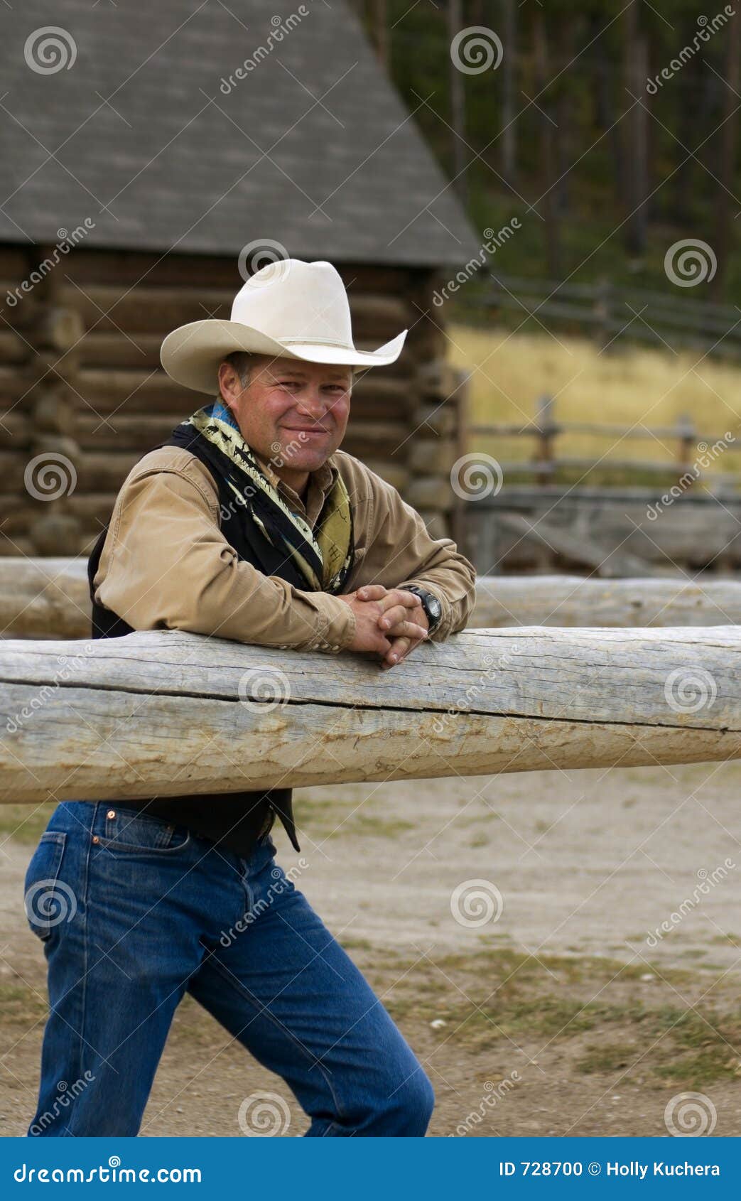 cowboy leans on fence